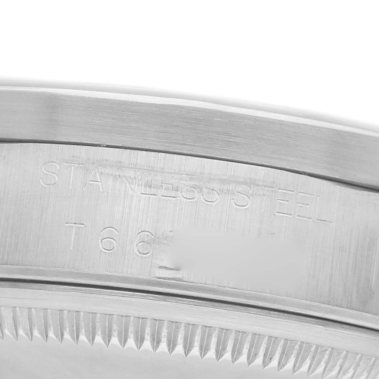 The image shows a close-up of the side of a Rolex Date 15210 Men's Stainless Steel Black Dial watch, focusing on the engraved stainless steel casing and fluted bezel edge.
