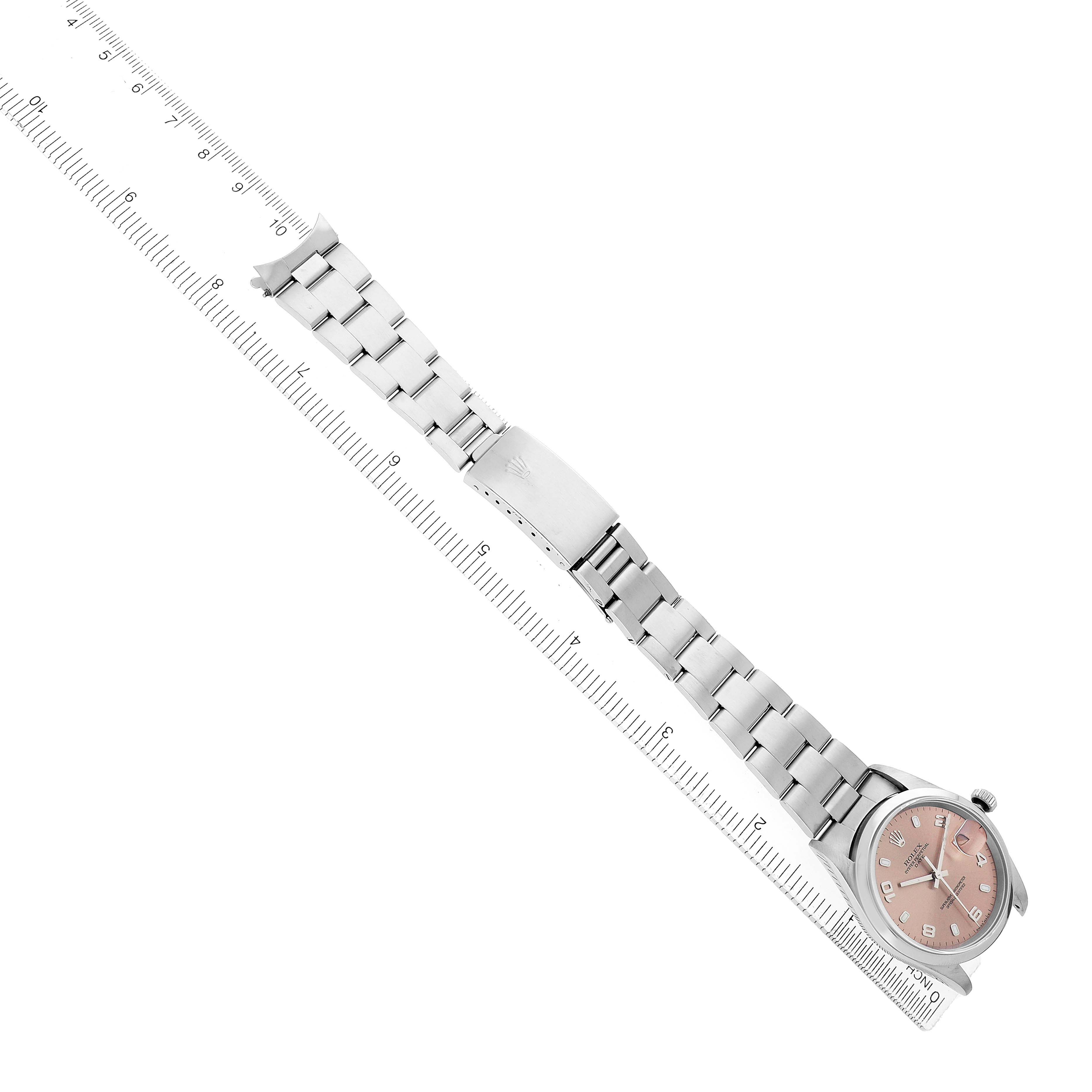 The Rolex Date 15200 Men's Stainless Steel Pink Dial watch is shown from an overhead angle, displaying the full bracelet, clasp, and face in alignment with a ruler.