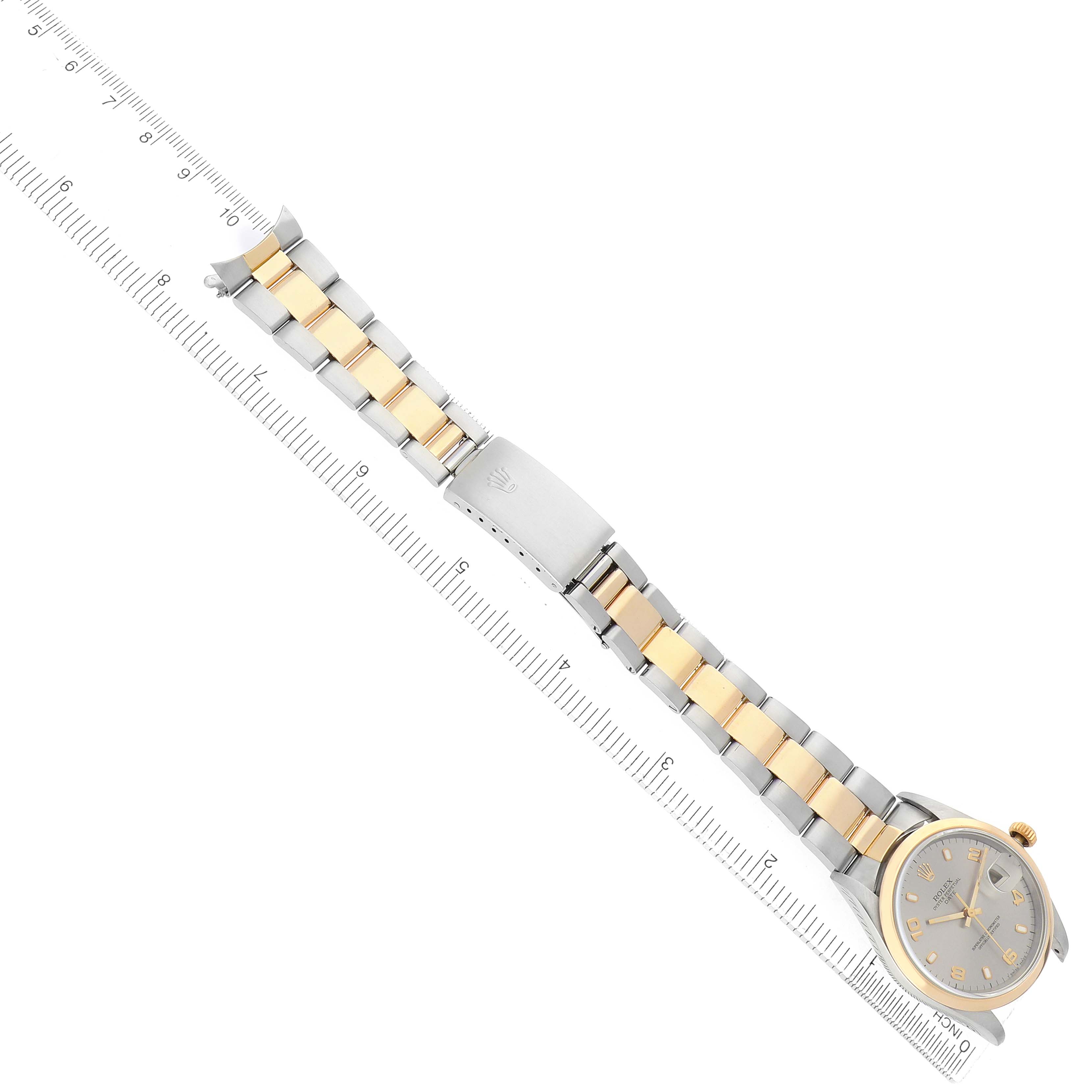 The image shows a Rolex Date 15203 Men's Steel and Gold (two tone) Grey Dial watch from a top-down angle, highlighting the bracelet and face next to a ruler.