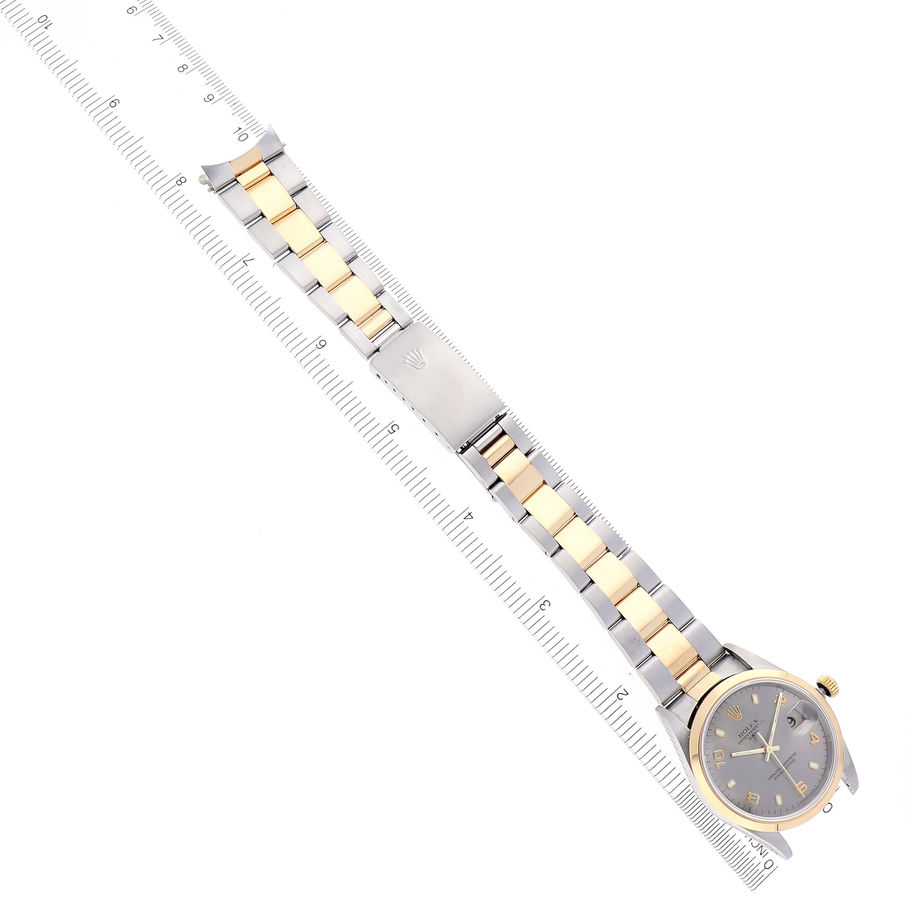 The image shows a top-down view of a Rolex Date 15203 Men's Steel and Gold (two tone) Grey Dial 15203 Men's Steel and Gold (two tone) Grey Dial watch, highlighting the face, bracelet, and clasp against a ruler for scale.