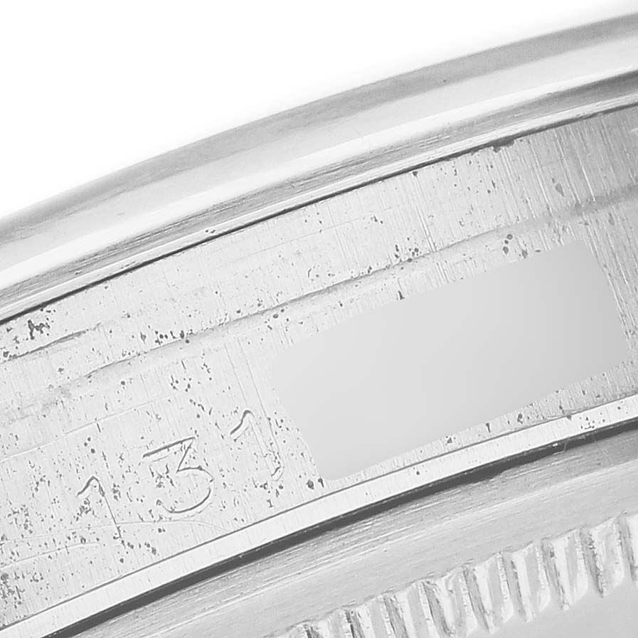 The image shows a close-up of the engraved bezel and outer edge of a Rolex Date 66579 Men's Stainless Steel White Dial 66579 Men's Stainless Steel White Dial model watch.
