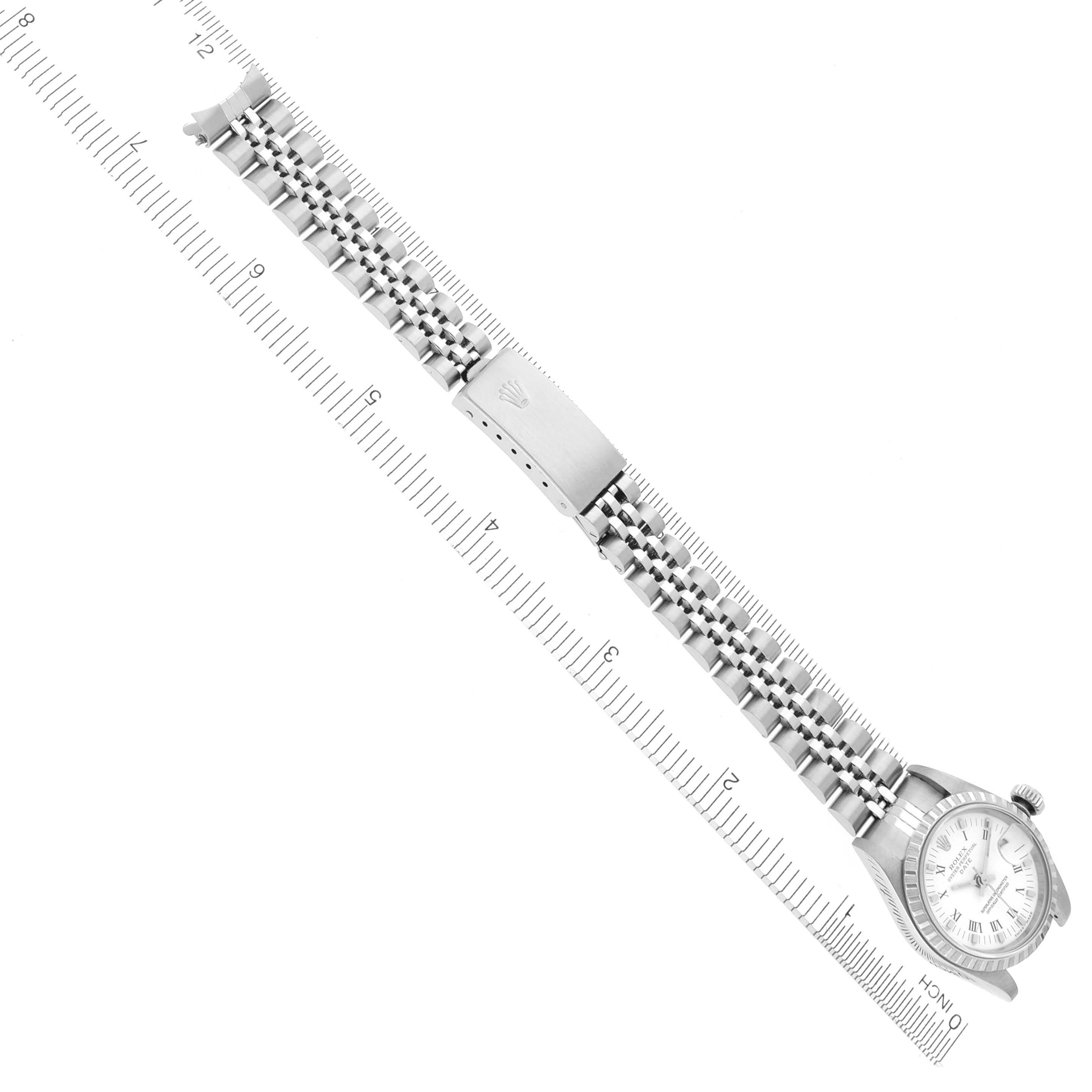 The image shows a Rolex Date 79240 Women
s Stainless Steel White Dial 79240 Women
s Stainless Steel White Dial watch from a top-down angle, highlighting its bracelet and clasp alongside a ruler for scale.