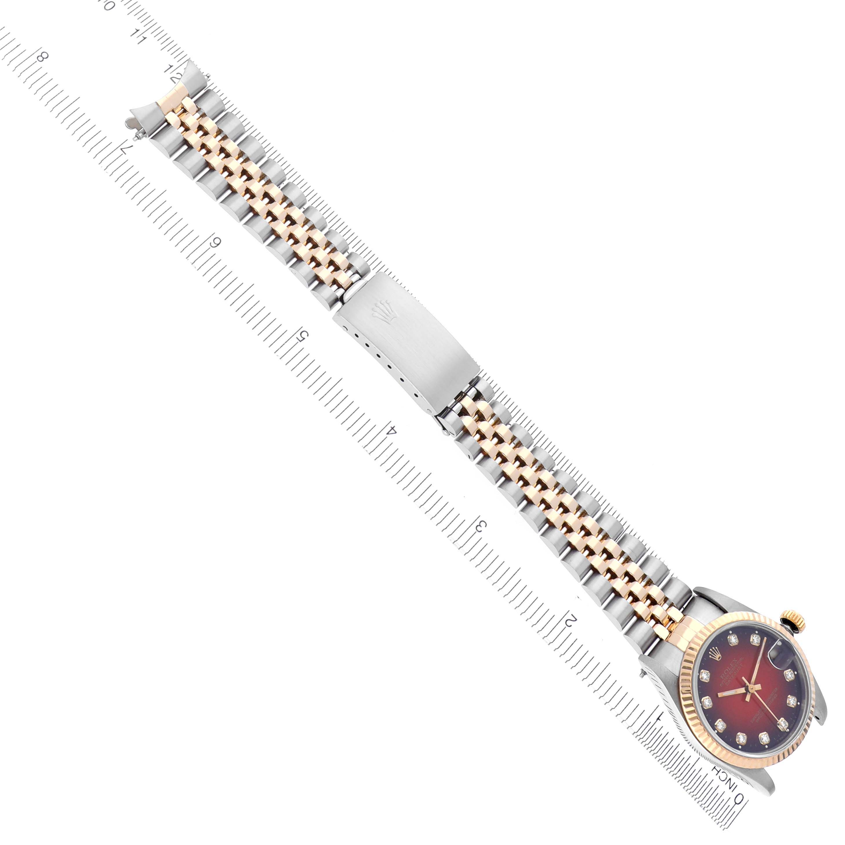 The Rolex Mid-Size 68273 Women's Steel and Gold (two tone) Red Dial 68273 Women's Steel and Gold (two tone) Red Dial watch is shown from above, displaying the face, two-tone bracelet, and clasp alongside a ruler for scale.