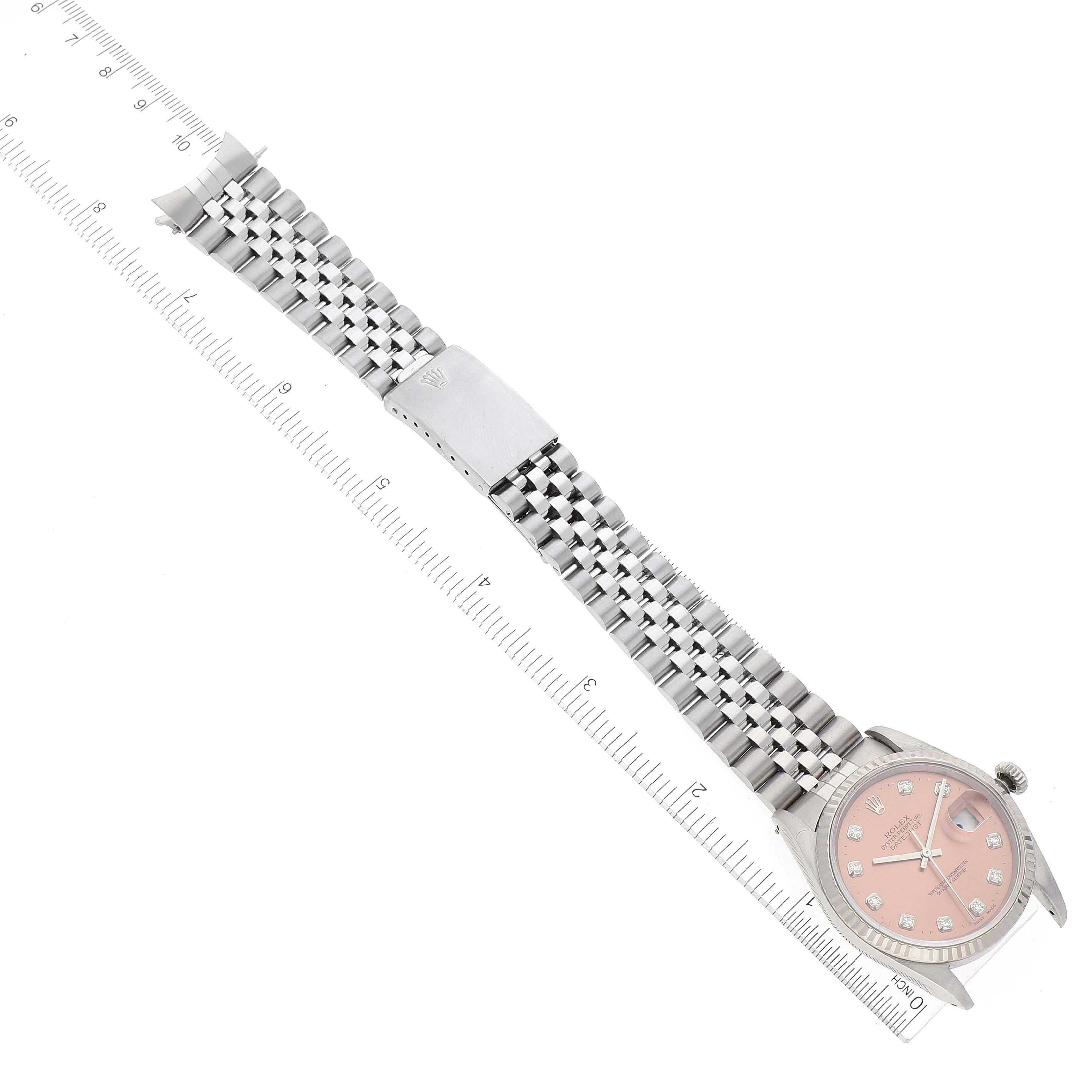 The image shows a Rolex Datejust 16234 Men's Stainless Steel Pink Dial 16234 Men's Stainless Steel Pink Dial watch from a top view, displaying the entire band, clasp, and face with a ruler alongside for scale.
