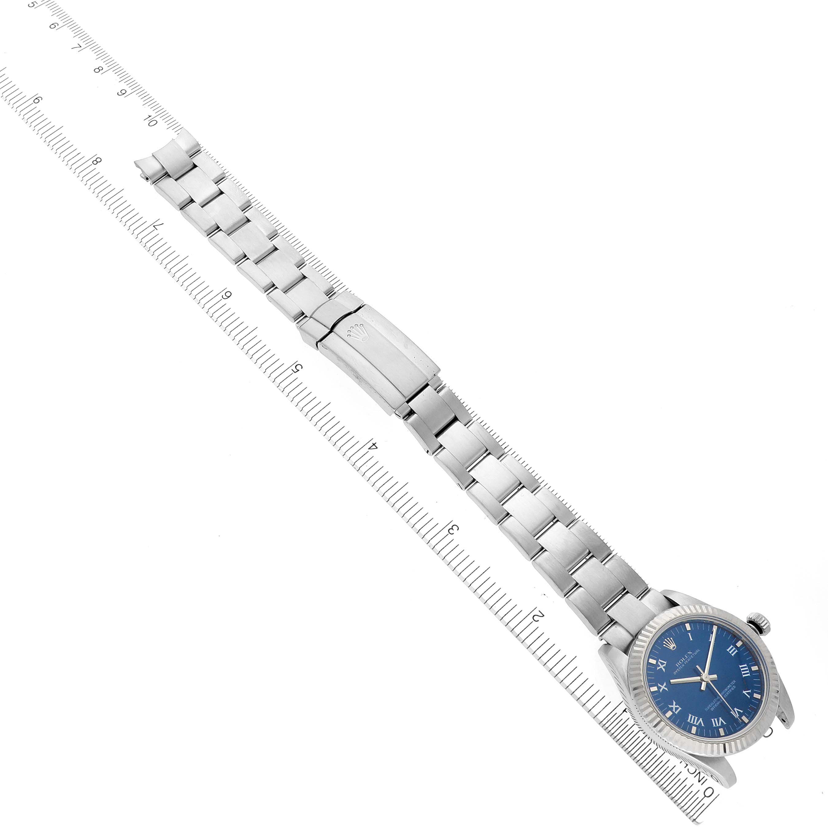 The Rolex Mid-Size 177234 Women
s Stainless Steel Blue Dial 177234 Women
s Stainless Steel Blue Dial watch is shown at an angle highlighting the blue dial, bracelet, and clasp with a measuring scale beside it.