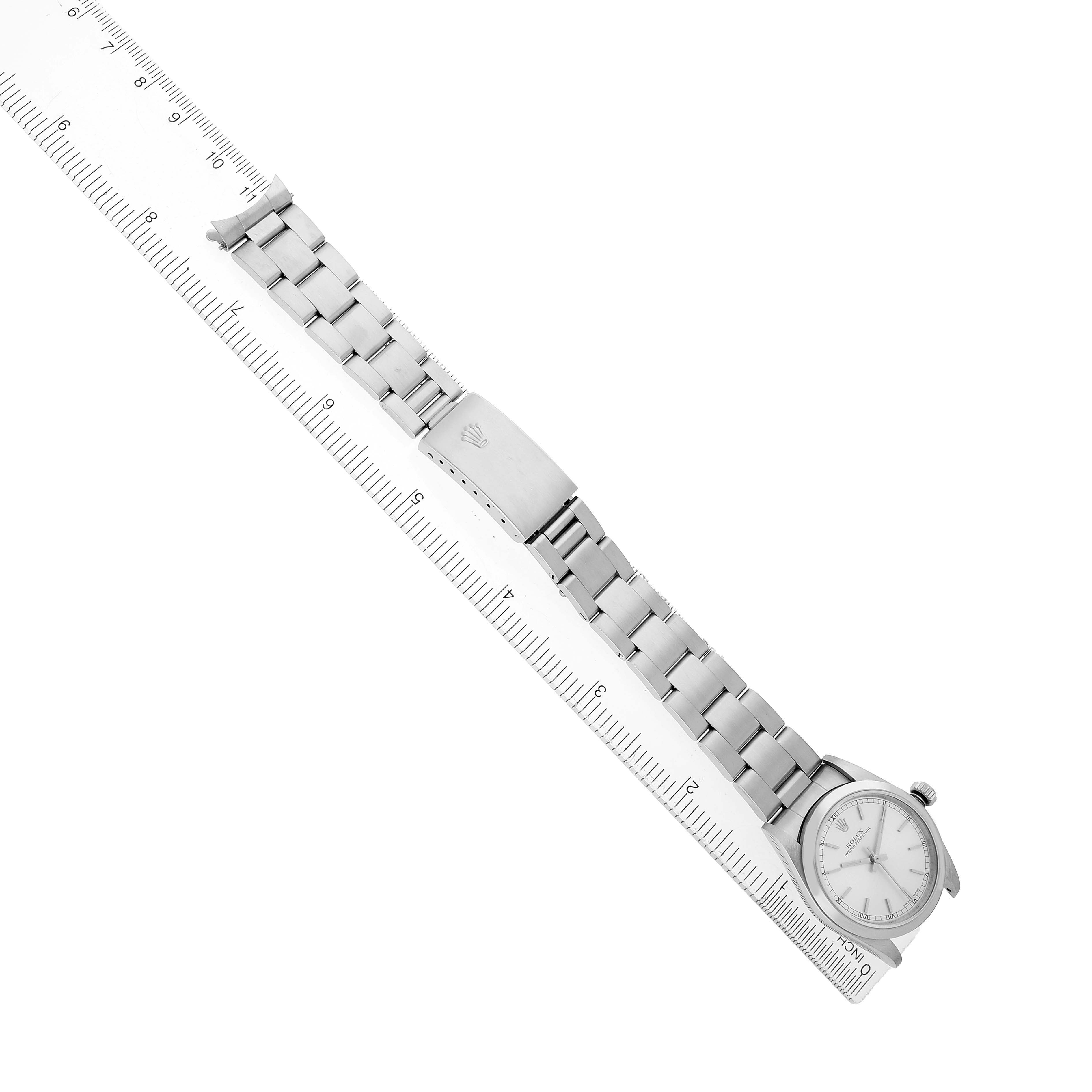 The Rolex Mid-Size 77080 Women's Stainless Steel Silver Dial watch is shown from a top-down angle, featuring its full bracelet alongside a measuring ruler.