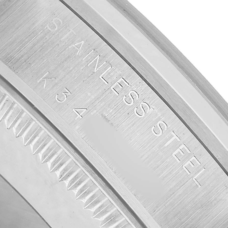 The image shows the edge of a Rolex Mid-Size 77080 Women's Stainless Steel Silver Dial watch case, highlighting the engraved text and serrated edge.