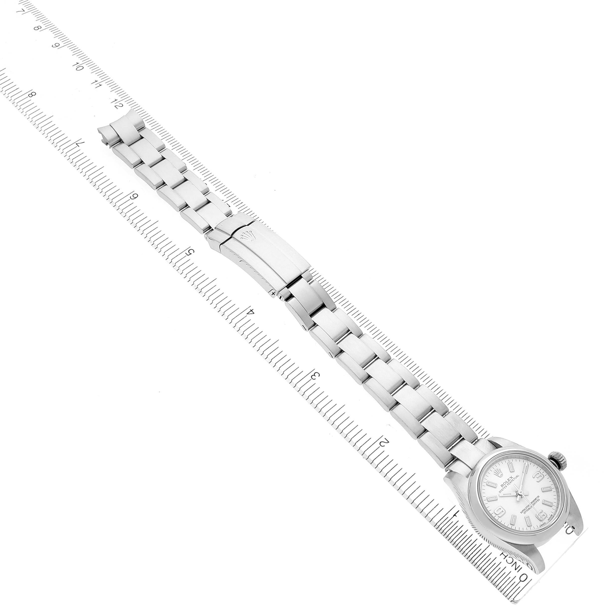 The Rolex Oyster Perpetual 176200 Women's Stainless Steel White Dial 176200 Women's Stainless Steel White Dial watch is shown from a top view, displaying the face, bracelet, clasp, and part of a measuring ruler.