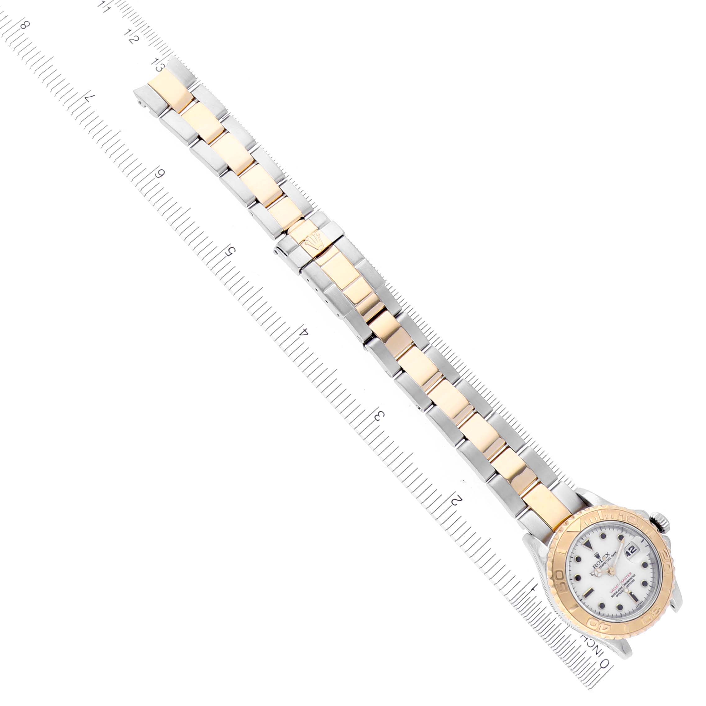 The Rolex Yacht-Master 69623 Women
s Steel and Gold (two tone) White Dial 69623 Women
s Steel and Gold (two tone) White Dial is shown from a top-down angle, displaying the bracelet, bezel, and face next to a ruler for scale.
