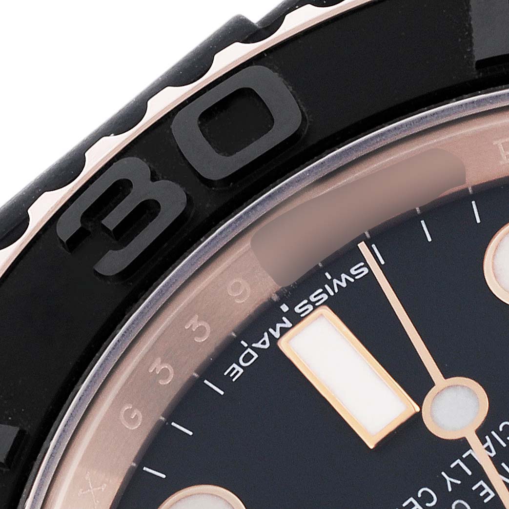 The image shows a close-up of the Rolex Yacht-Master 116655 Men's Rose Gold Black Dial 116655 Men's Rose Gold Black Dial's bezel and part of the dial, including an hour marker.
