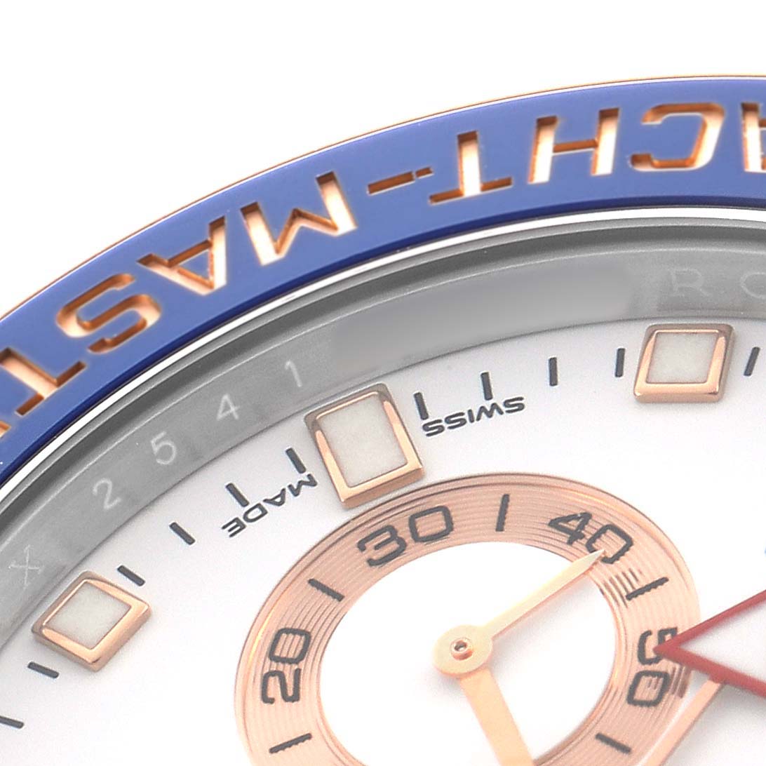 The image shows a close-up of the Rolex Yacht-Master 116681M Men's Steel and Gold (two tone) White Dial's blue bezel and part of the watch face with numerals and hands.