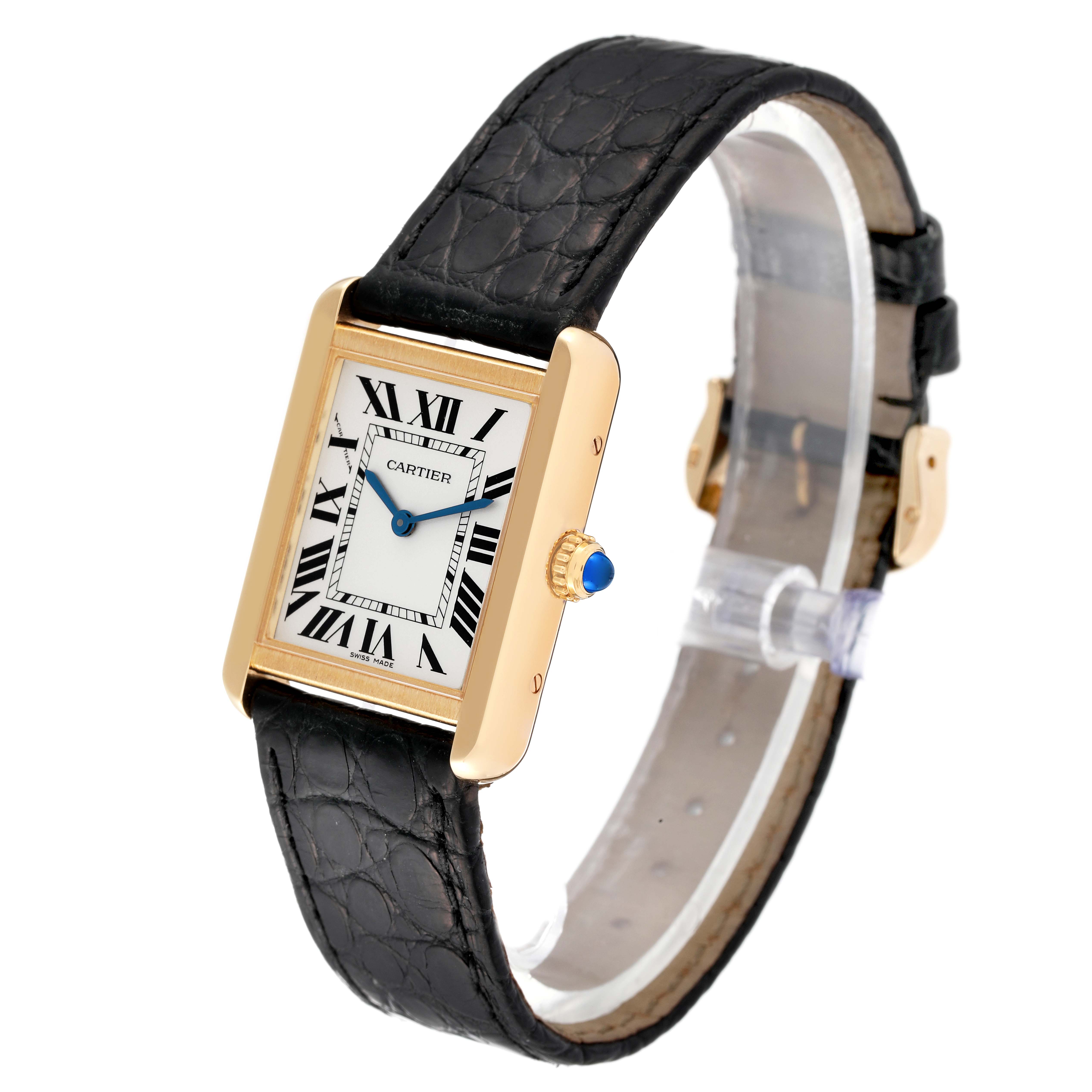 The image shows a Cartier Tank Solo W5200002 Women
s Stainless Steel Silver Dial W5200002 Women
s Stainless Steel Silver Dial watch at an angle, displaying its face, gold bezel, black leather strap, and blue cabochon crown.