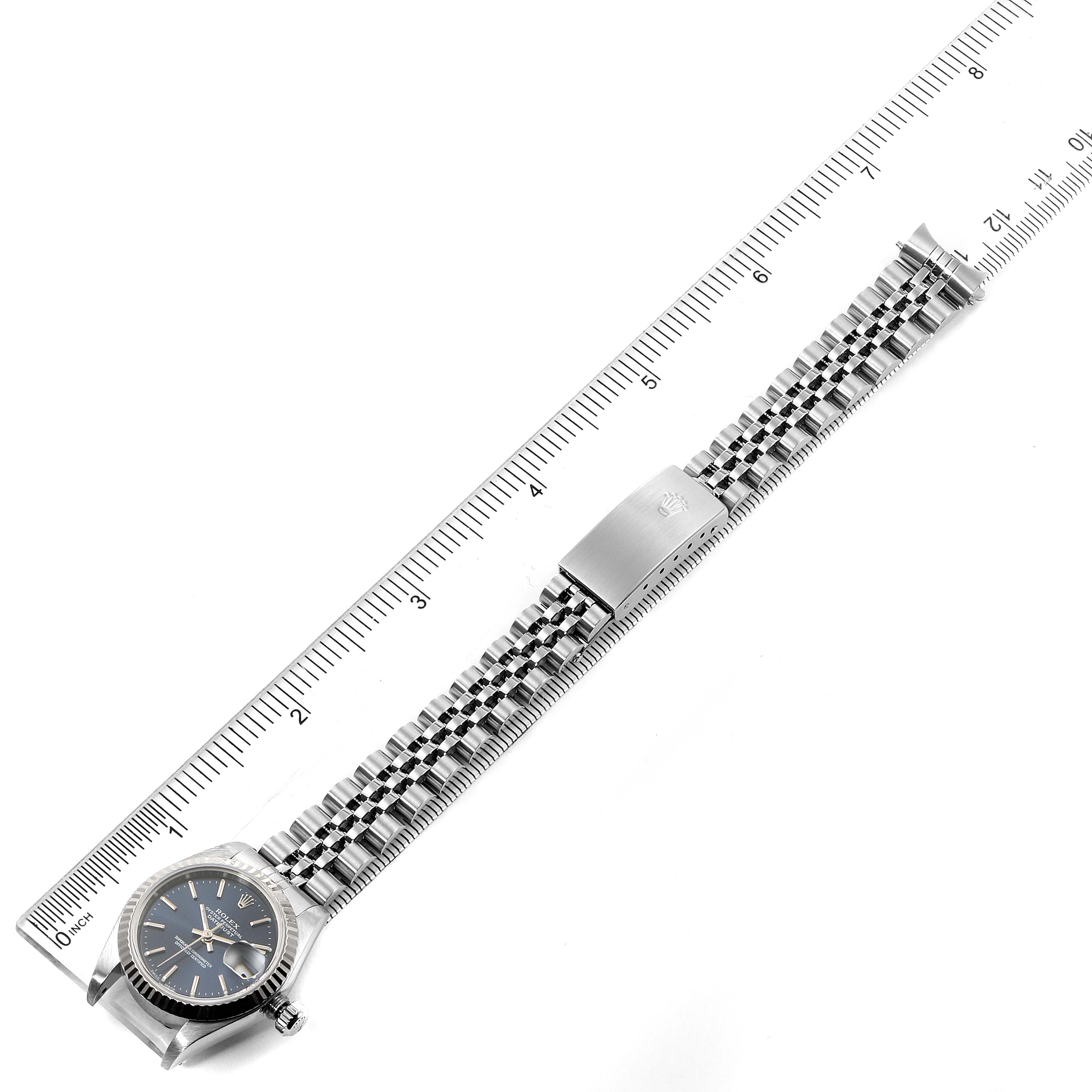 The image shows the entire length of a Rolex Datejust 79174 Women's Stainless Steel Blue Dial 79174 Women's Stainless Steel Blue Dial watch laid flat beside a ruler, displaying the face, bracelet, and clasp.