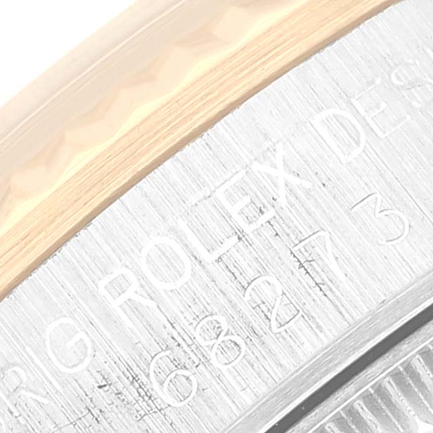 The image shows an angled close-up of the engraved bezel on a Mid-Size Rolex watch.