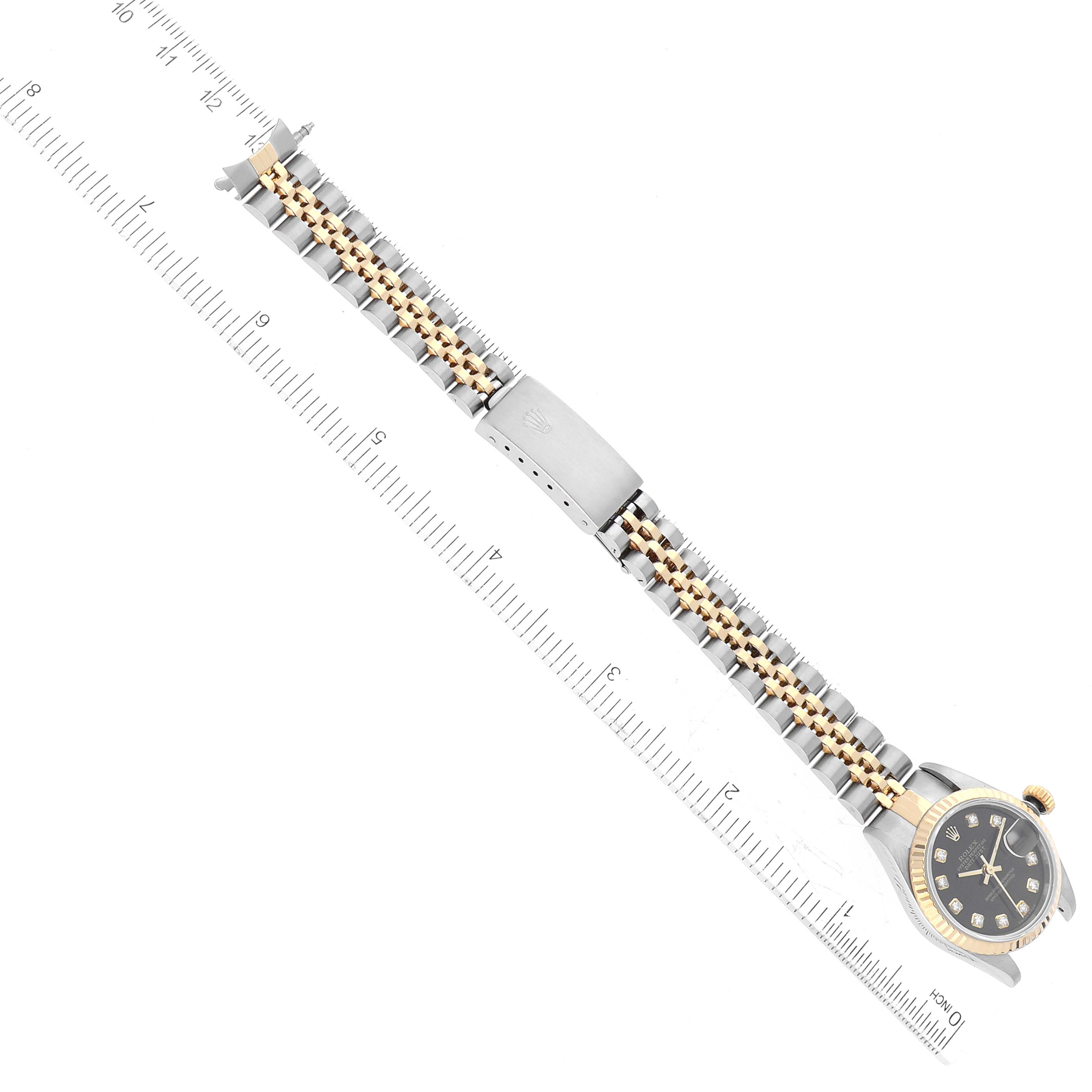 This image shows an overhead view of a Rolex Datejust 79173 Women's Steel and Gold (two tone) Black Dial 79173 Women's Steel and Gold (two tone) Black Dial with a two-tone bracelet, clasp, and ruler for scale.