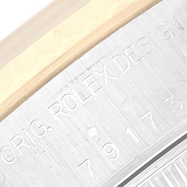 This close-up image displays the engraved text on the side of the case of a Rolex Datejust 79173 Women's Steel and Gold (two tone) Black Dial 79173 Women's Steel and Gold (two tone) Black Dial watch, showcasing part of its design and serial number.