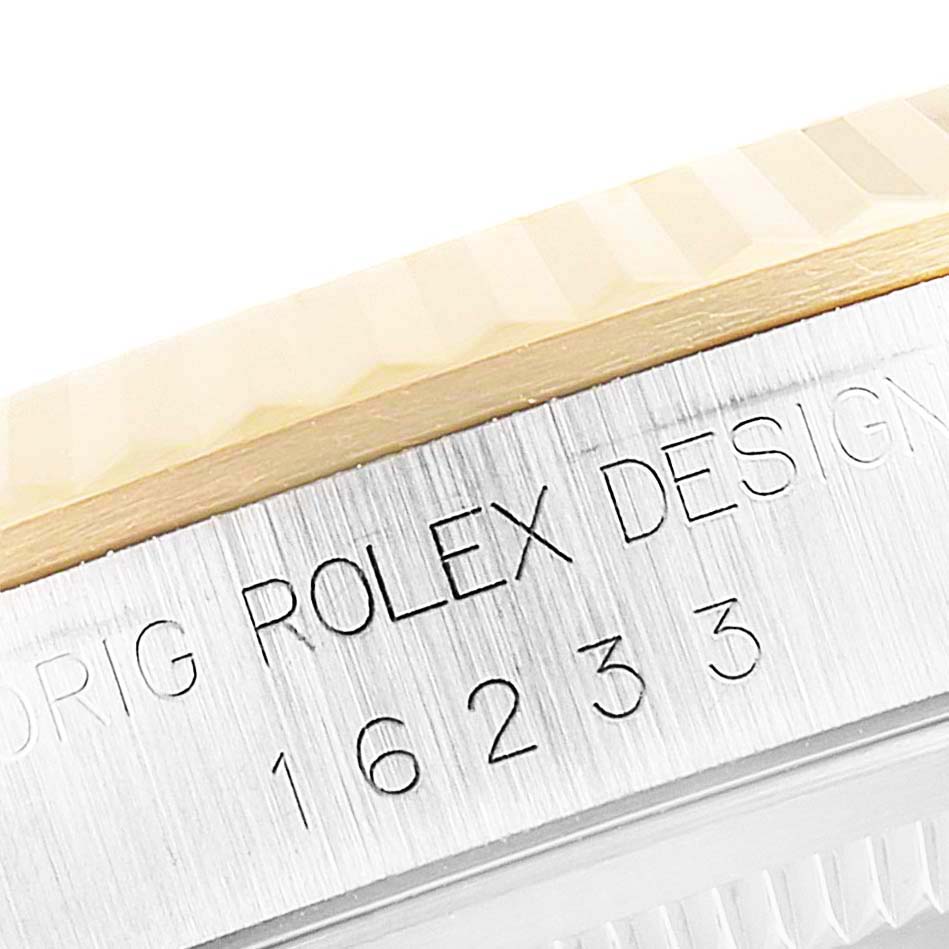 The image shows a close-up of the side engraving and fluted bezel of a Rolex Datejust 16233 Men's Steel and Gold (two tone) Black Dial 16233 Men's Steel and Gold (two tone) Black Dial model.