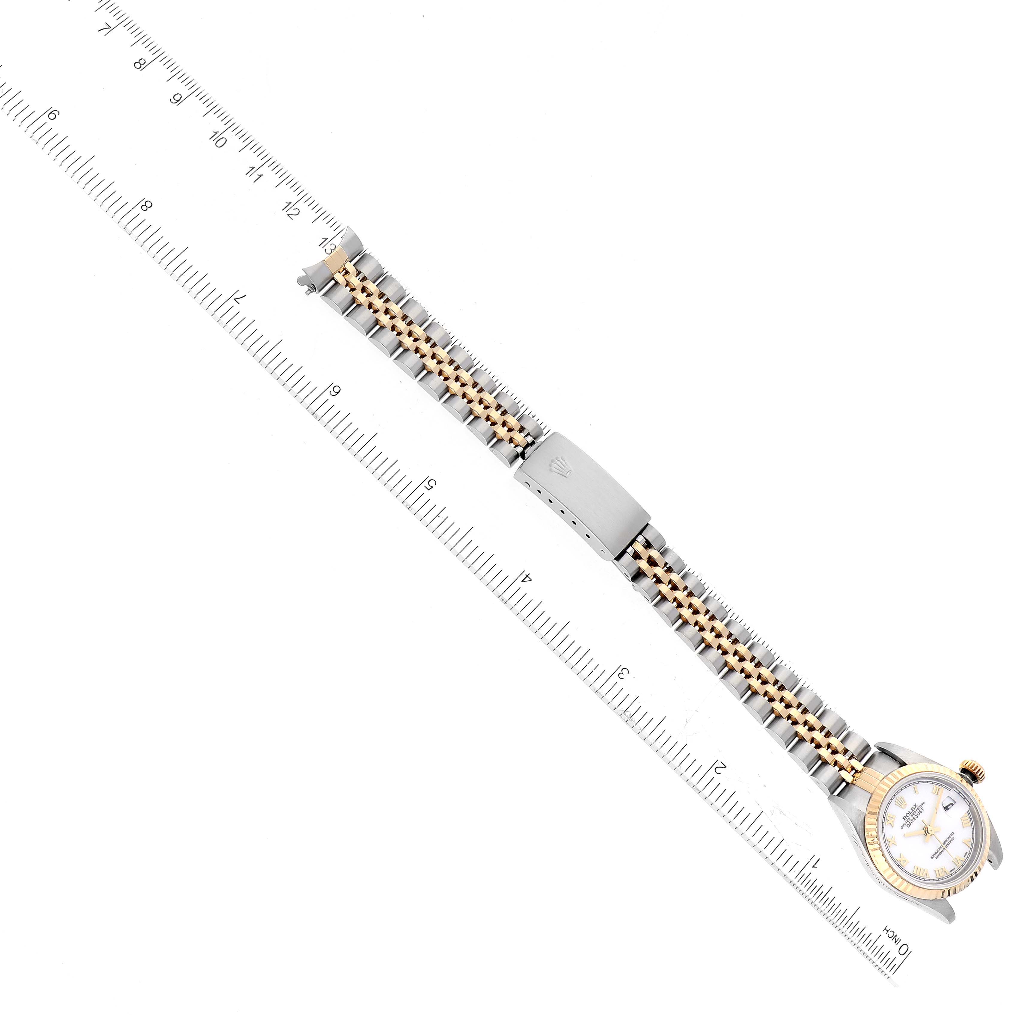 The image shows a top-down view of a Rolex Datejust 79173 Women's Steel and Gold (two tone) White Dial 79173 Women's Steel and Gold (two tone) White Dial watch with a two-tone bracelet and a ruler for scale.
