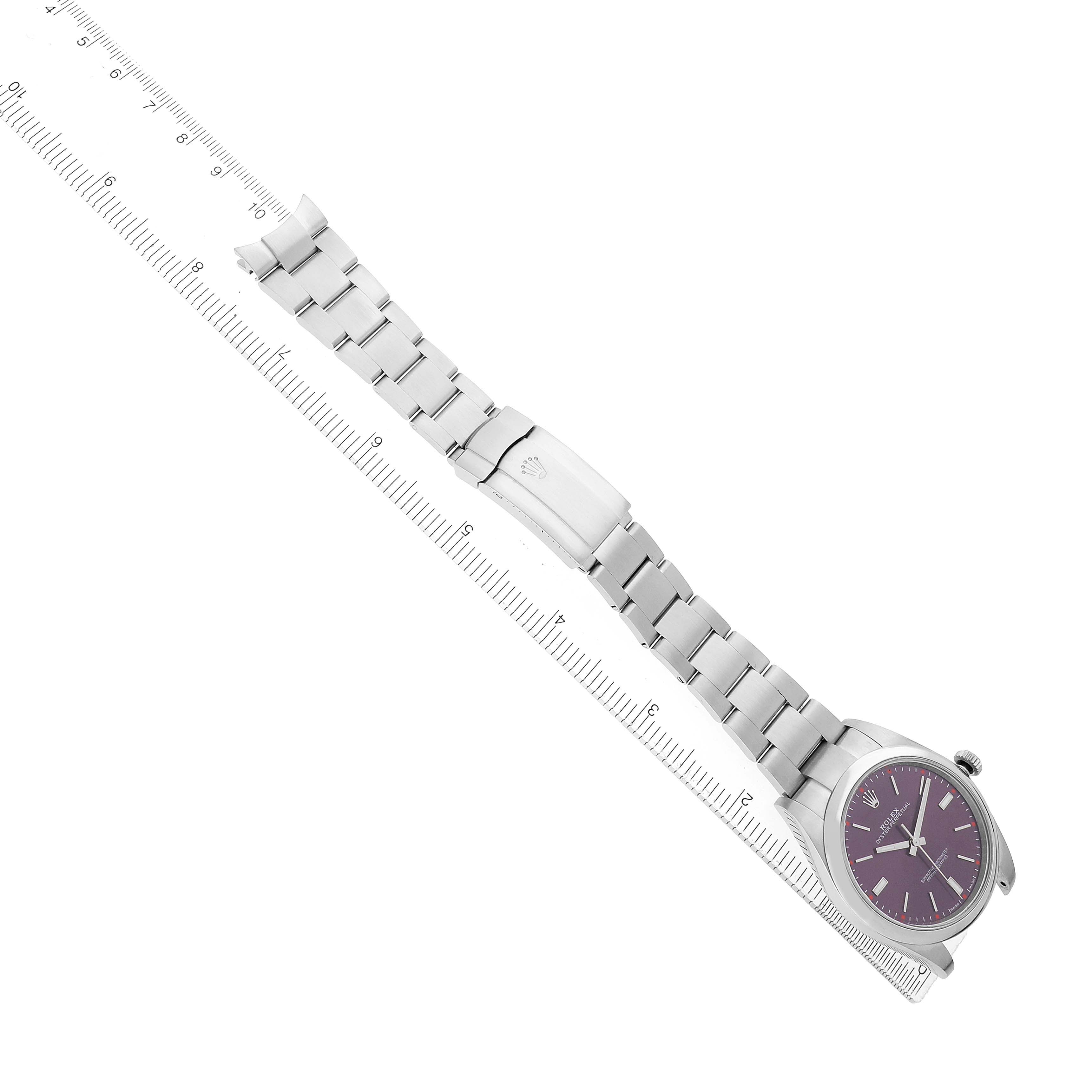 The Rolex Oyster Perpetual 114300 Men's Stainless Steel Purple Dial watch is shown diagonally, displaying its band and clasp alongside a ruler for scale.