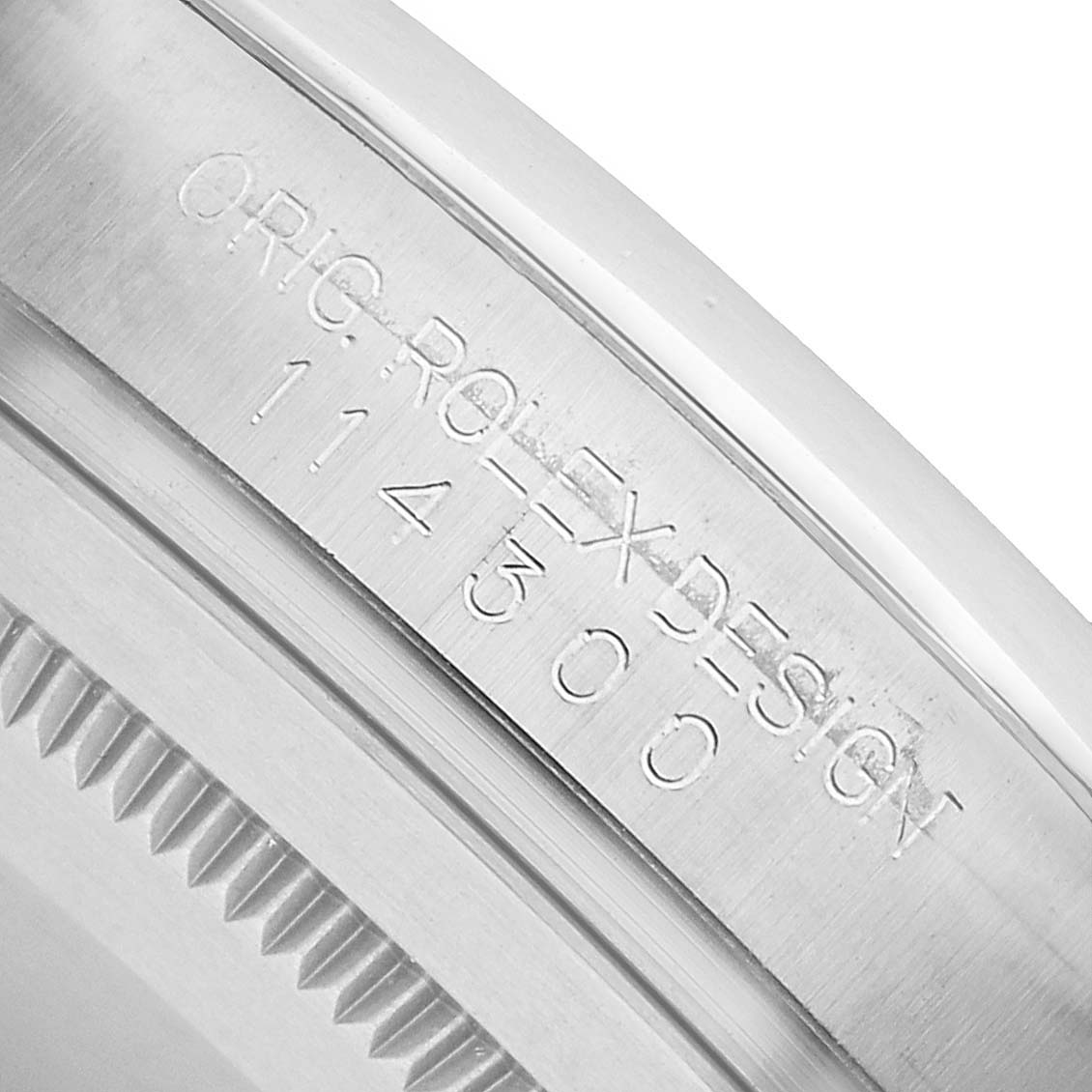 The image shows a close-up of the engraved inner bezel of the Rolex Oyster Perpetual 114300 Men's Stainless Steel Purple Dial, highlighting the "ORIG ROLEX DESIGN" text and model number.