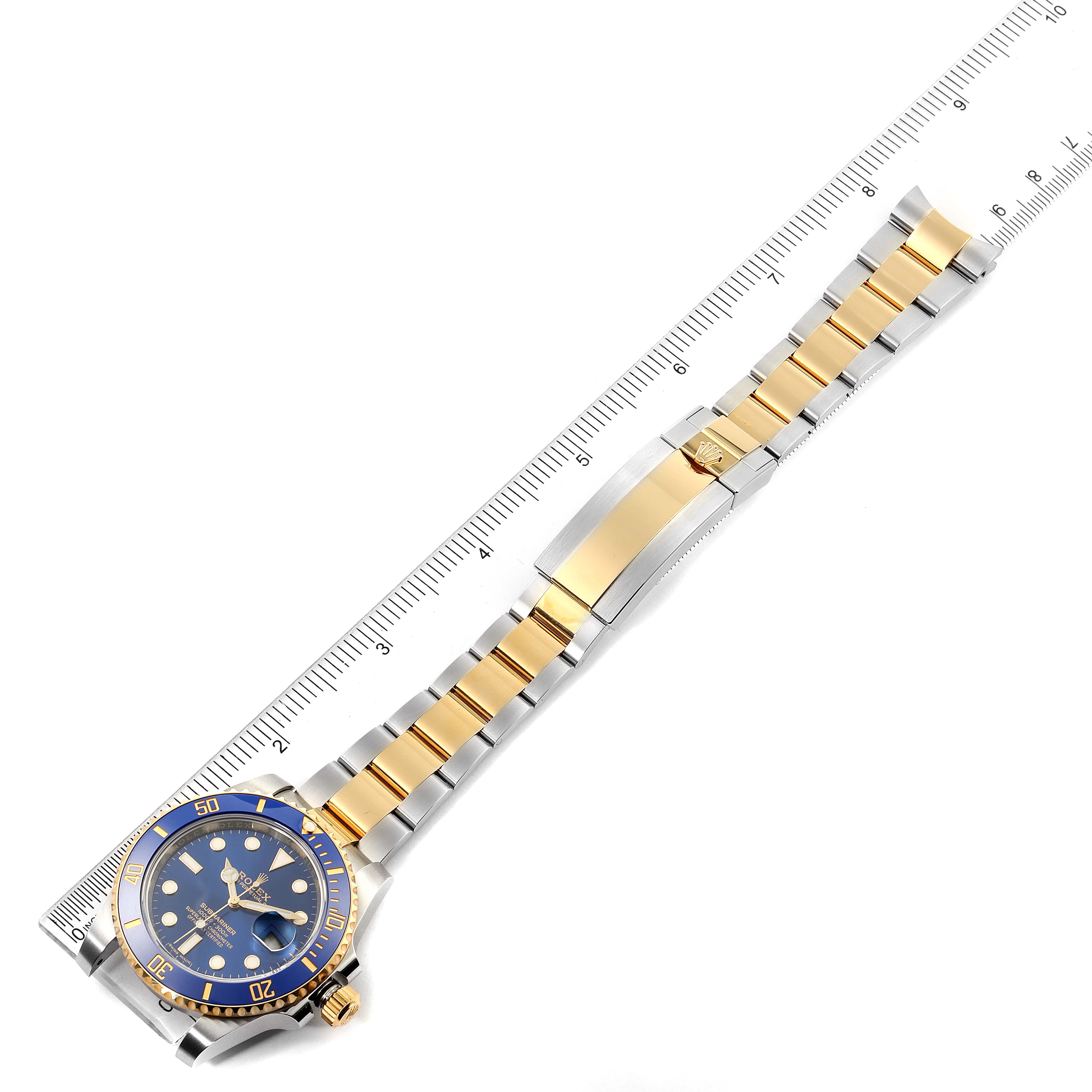 The Rolex Submariner 116613 Men's Steel and Gold (two tone) Blue Dial 116613 Men's Steel and Gold (two tone) Blue Dial watch is shown flat from above, with a ruler alongside, displaying the watch face, bezel, and bracelet.