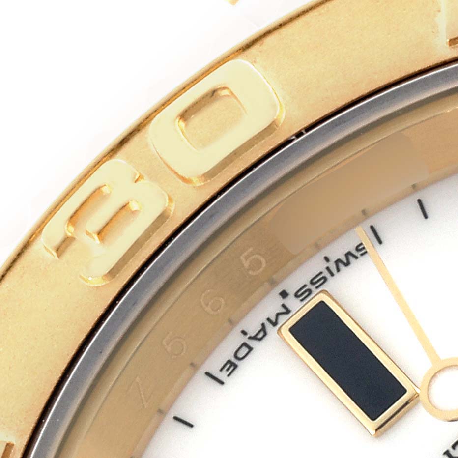 The image shows a close-up of the gold bezel and part of the dial of a Rolex Yacht-Master 16628 Men's Yellow Gold White Dial 16628 Men's Yellow Gold White Dial watch.