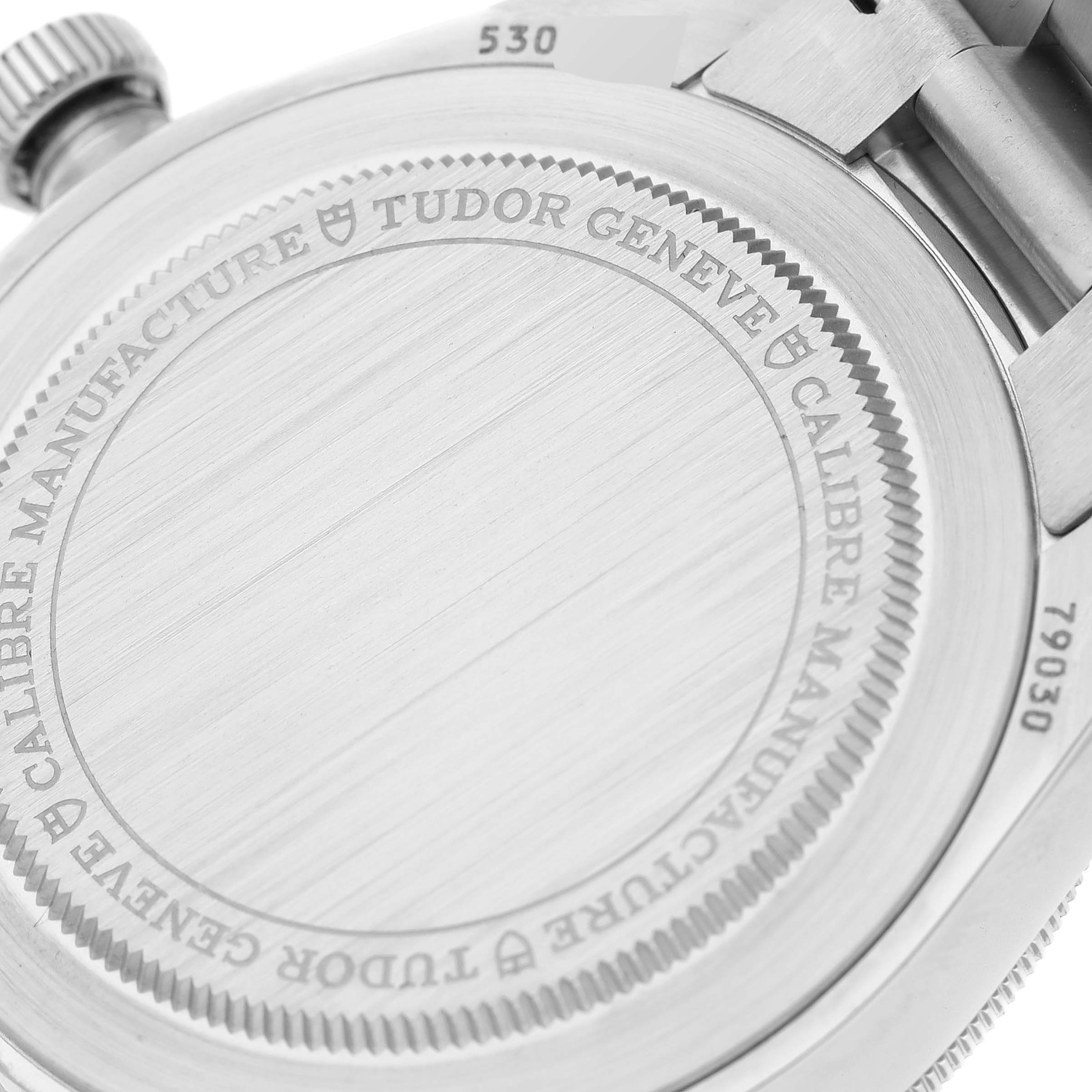 The image shows the back case of a Tudor Heritage Black Bay 79030 Men
s Stainless Steel Blue Dial 79030 Men
s Stainless Steel Blue Dial watch, focusing on its engraving and parts of the bracelet.