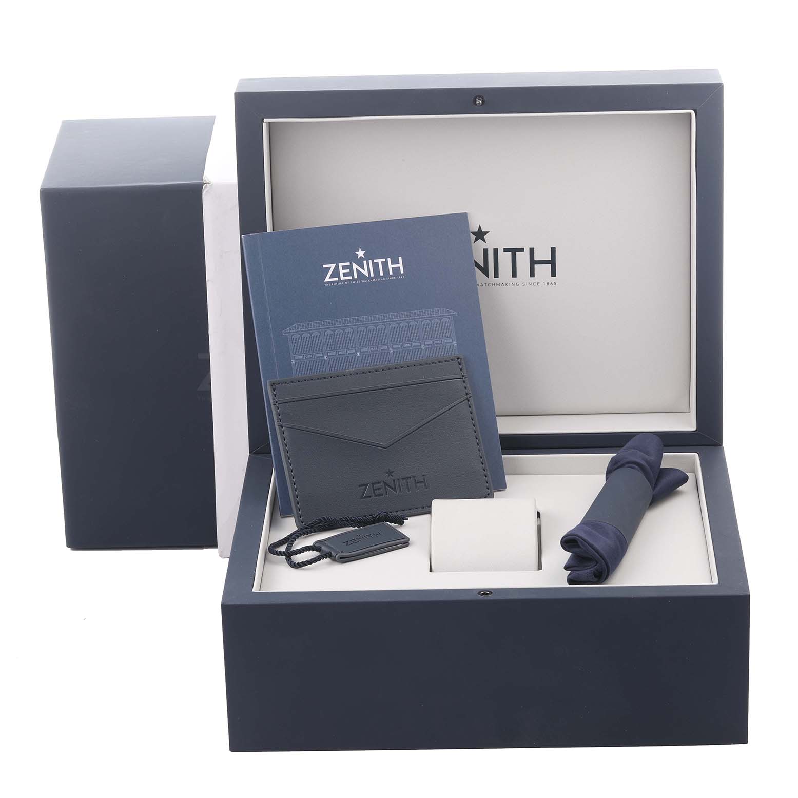 The image shows a top view of the Zenith Chronomaster 95.3100.3600.39.M3100 Men
s Titanium Silver Dial 95.3100.3600.39.M3100 Men
s Titanium Silver Dial box with accessories, including a booklet, cardholder, tag, and cloth.