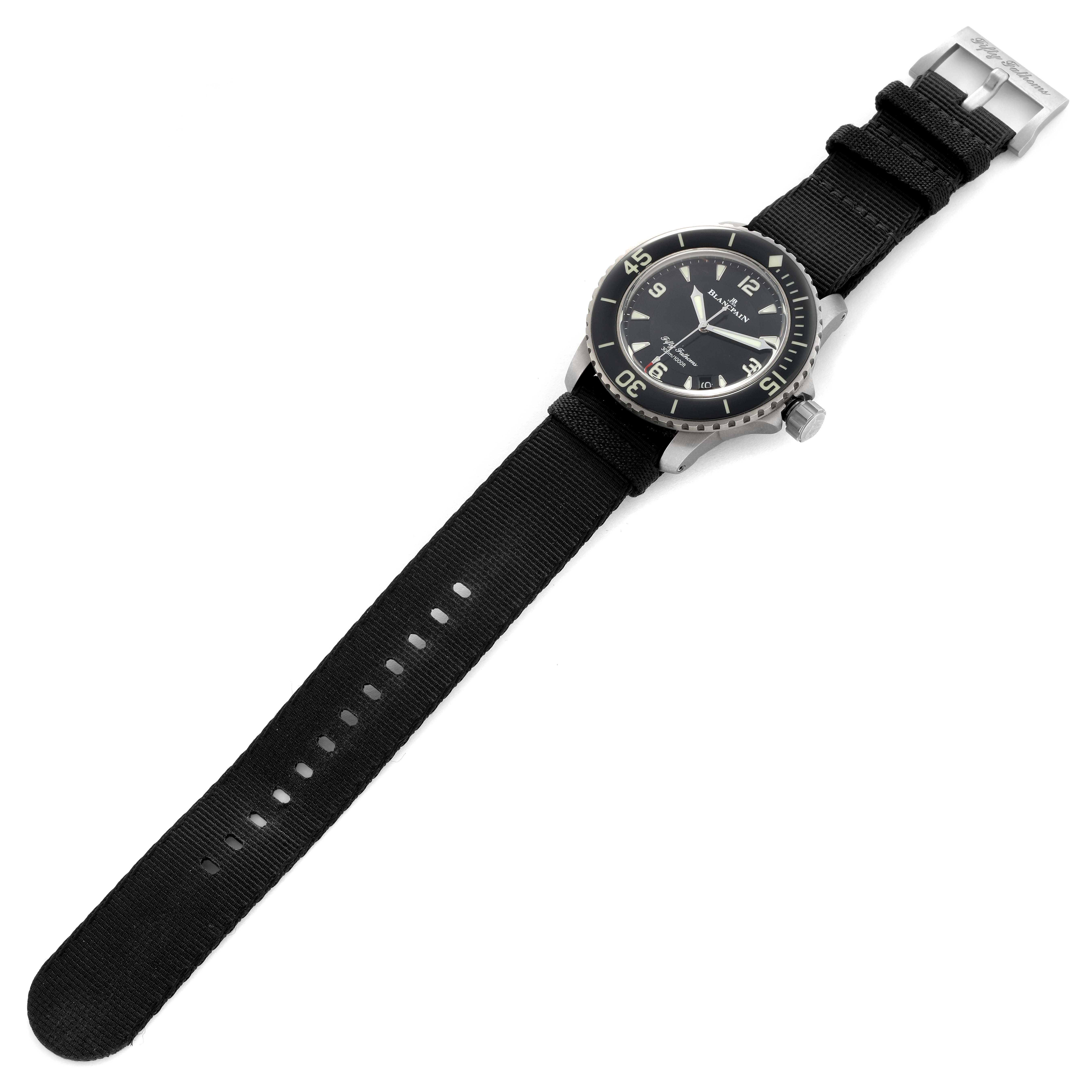The Blancpain Fifty Fathoms 5015-12B30 Men's Titanium Black Dial watch is shown from a top angle, displaying its face, bezel, strap, and buckle.