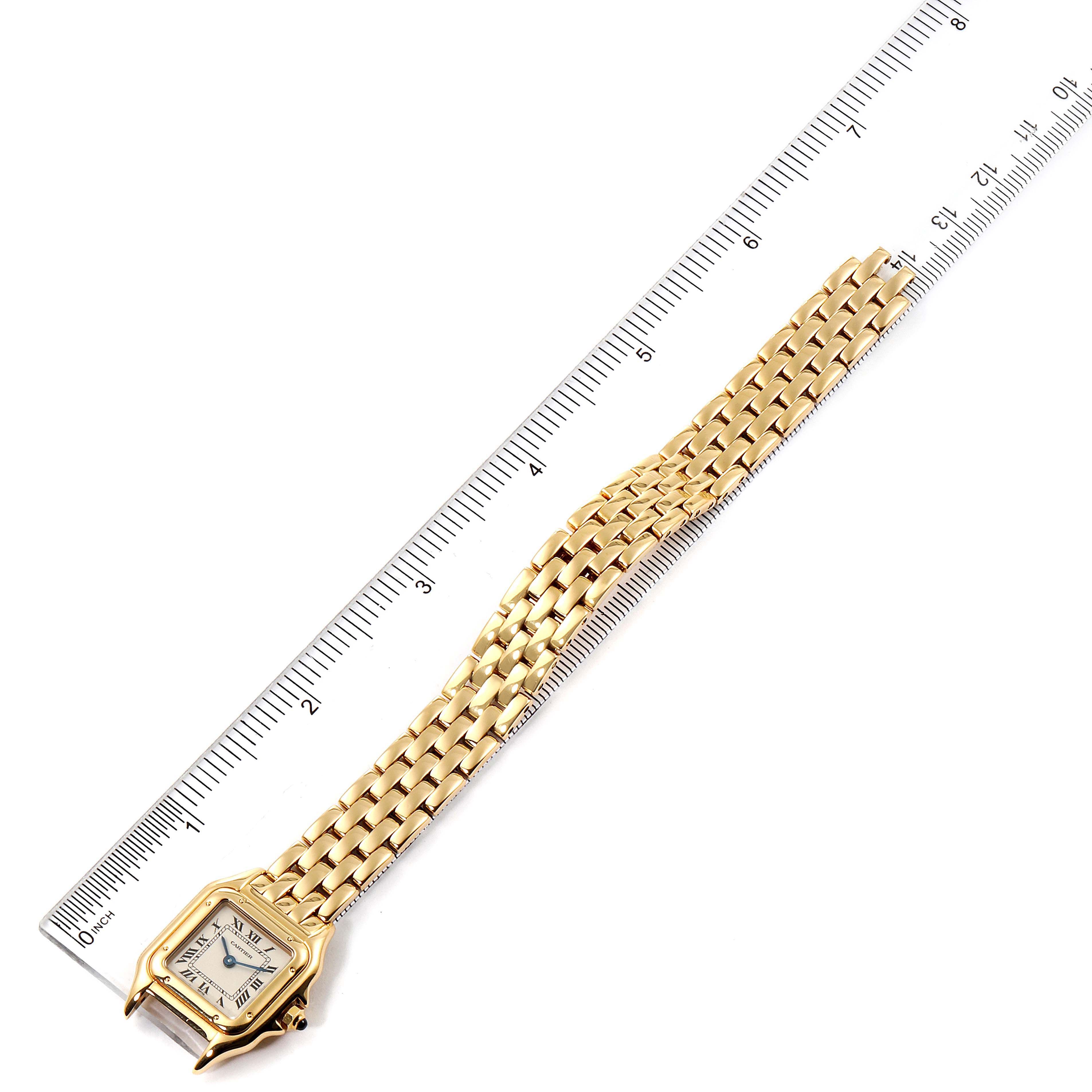 The Panthere de Cartier watch is shown from above, displaying its face and entire gold link bracelet next to a ruler for scale.