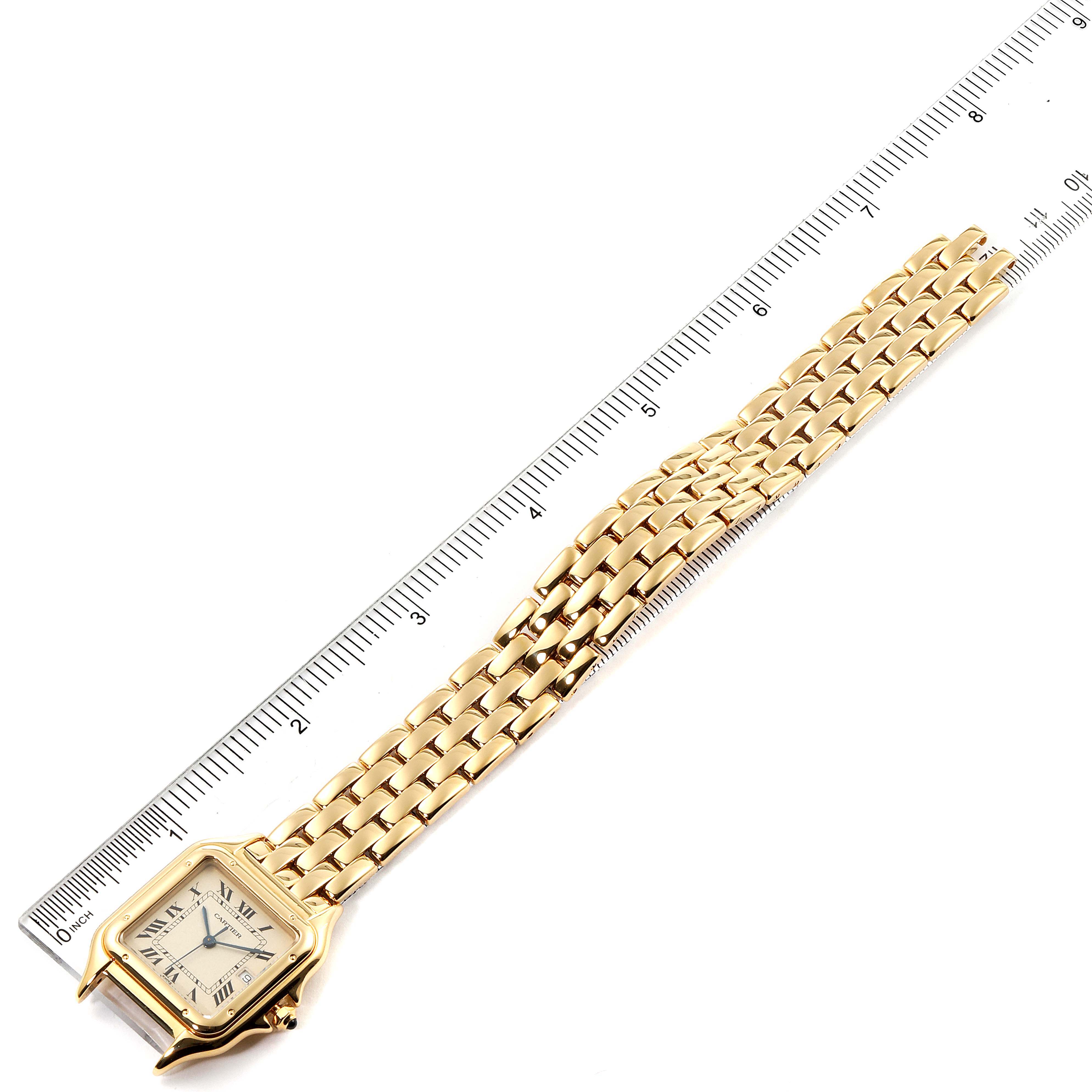 This image shows a gold Panthere model by Cartier with the face and bracelet next to a ruler for scale, viewed from above.