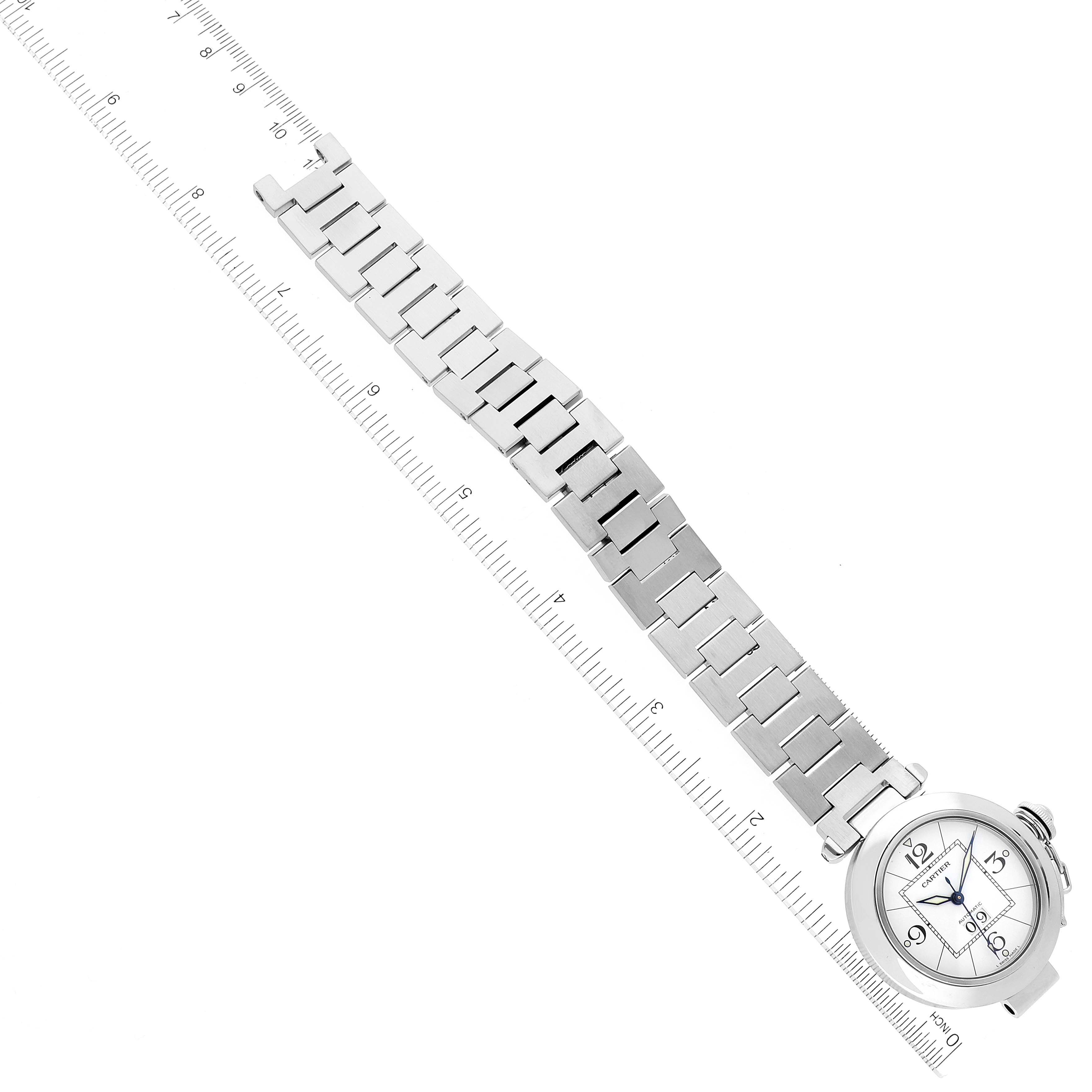 This image shows a top-down view of the Cartier Pasha W31055M7 Women's Stainless Steel White Dial W31055M7 Women's Stainless Steel White Dial watch and its metal bracelet aligned with a ruler.