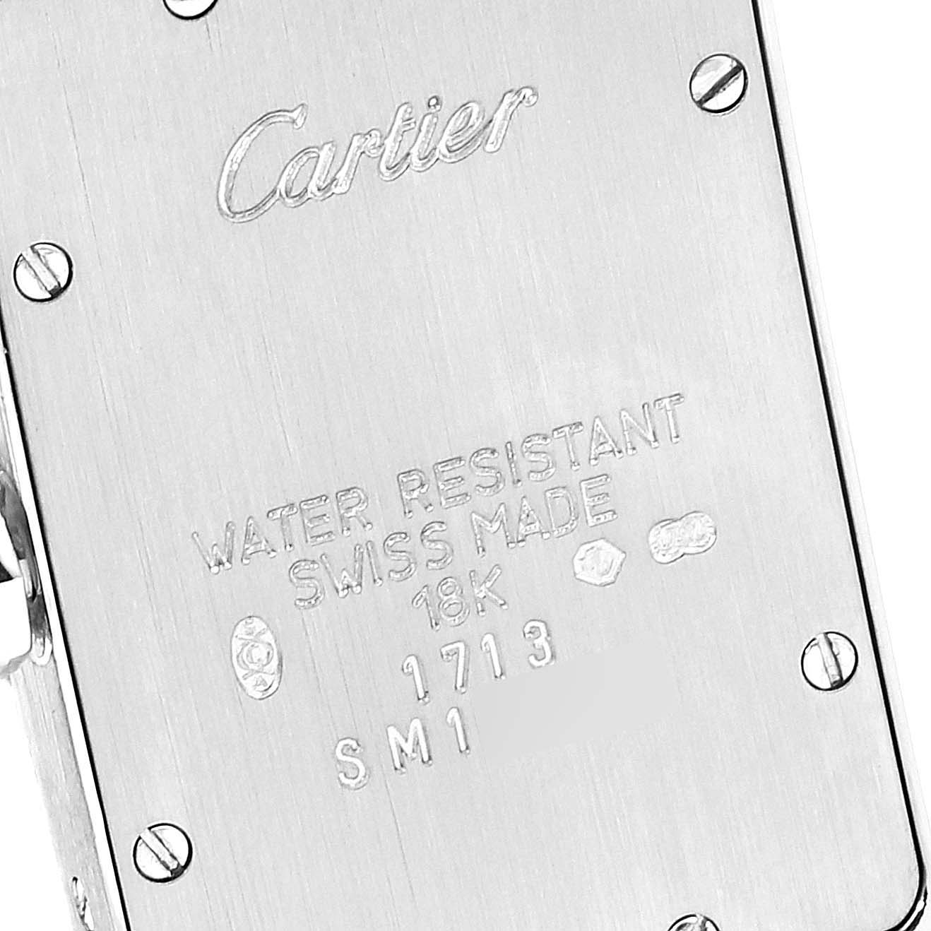 The image shows the back casing of a Tank Americaine watch by Cartier, featuring engraved details and securing screws.