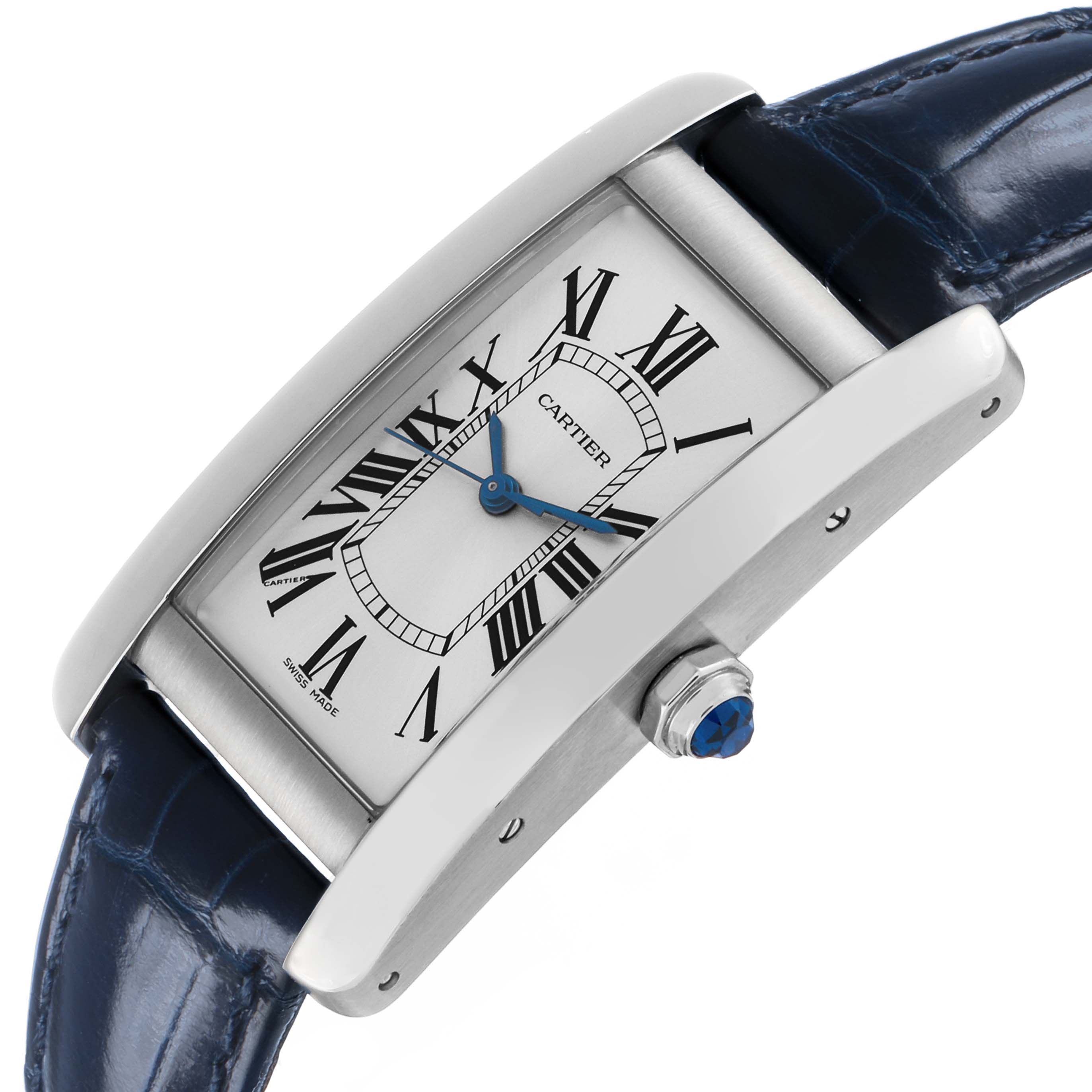 The Cartier Tank Americaine WSTA0017 Women's Stainless Steel Silver Dial watch is shown at an angle highlighting its rectangular face, Roman numerals, blue hands, and side crown.