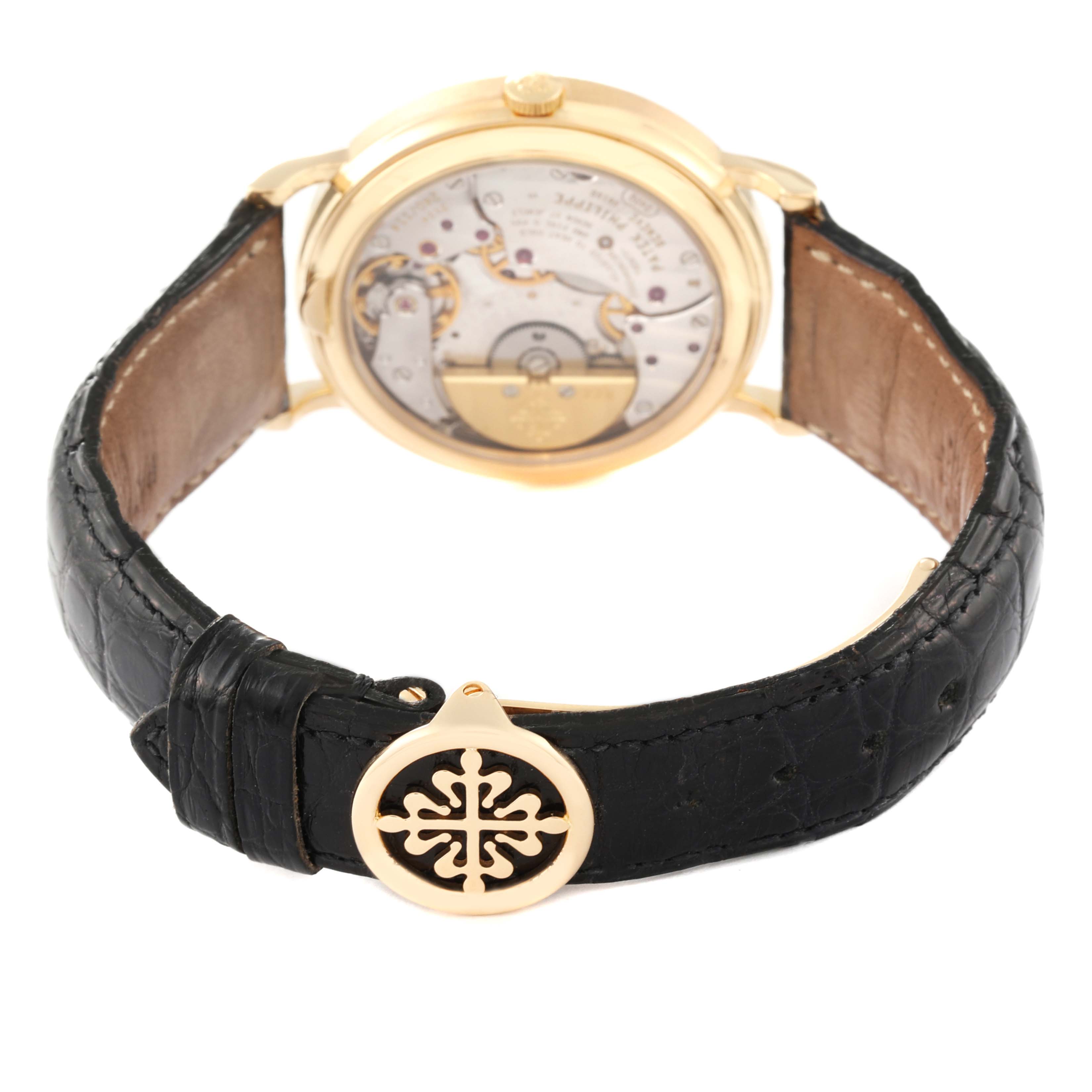 The image shows the back view of the Patek Philippe Complications 5039J Men's Yellow Gold Silver Dial 5039J Men's Yellow Gold Silver Dial model, highlighting its mechanical movement and black leather strap.