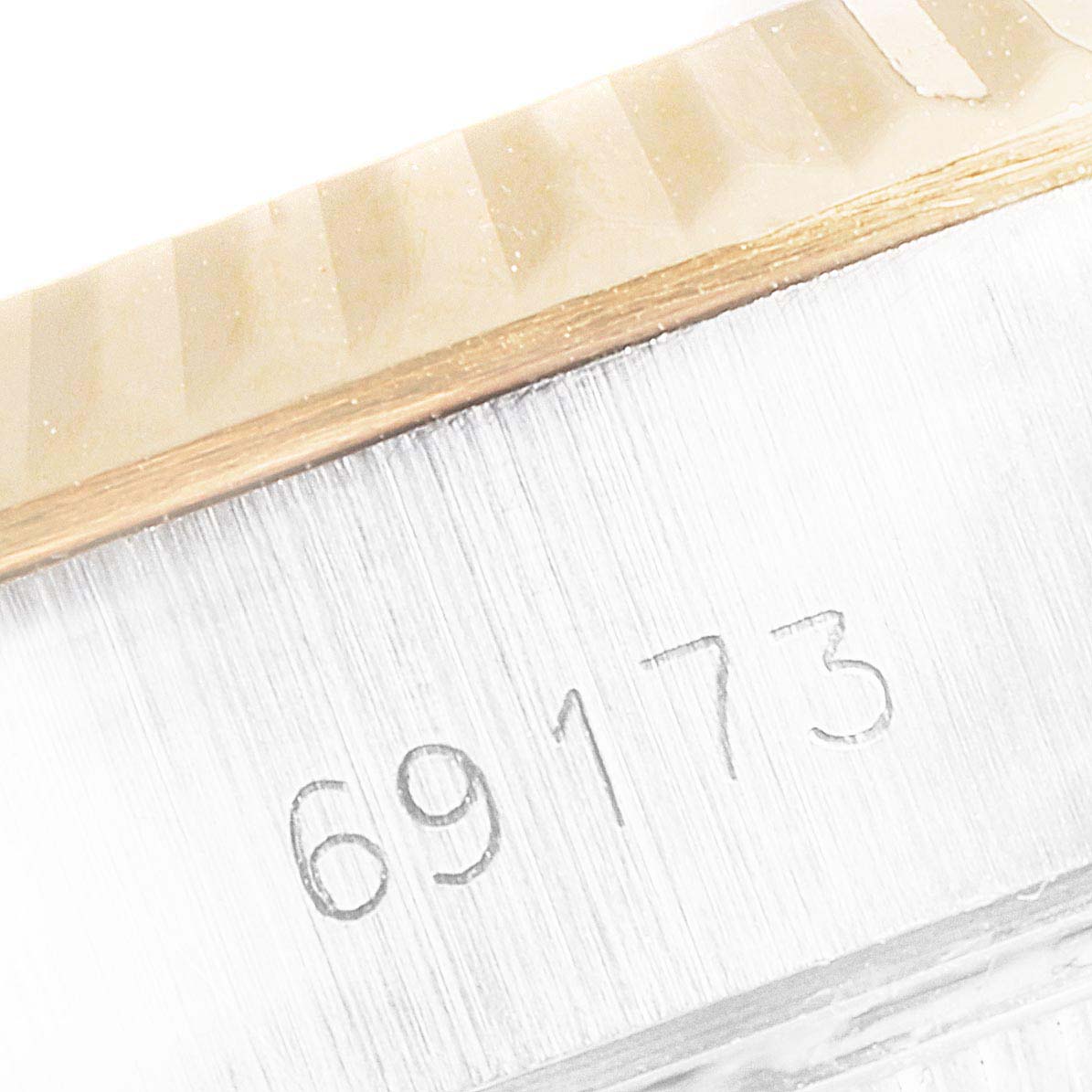 This close-up image shows the case and part of the fluted bezel of a Rolex Datejust 69173 Women
s Steel and Gold (two tone) Champagne Dial 69173 Women
s Steel and Gold (two tone) Champagne Dial watch, with the serial number "69173" engraved.