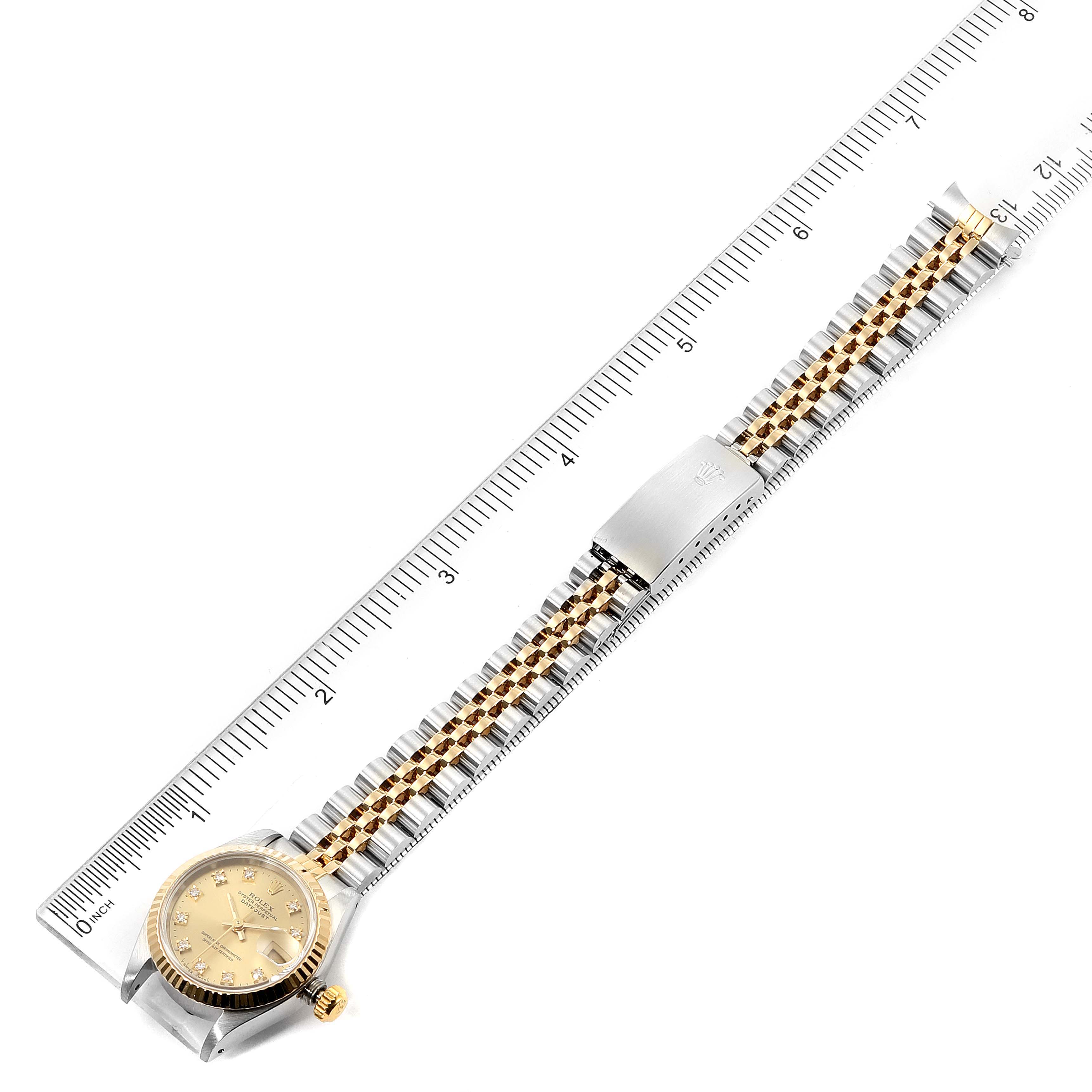 This image shows a Rolex Datejust 69173 Women
s Steel and Gold (two tone) Champagne Dial 69173 Women
s Steel and Gold (two tone) Champagne Dial watch in a top-down view, featuring its full length and positioned alongside a ruler for size reference.