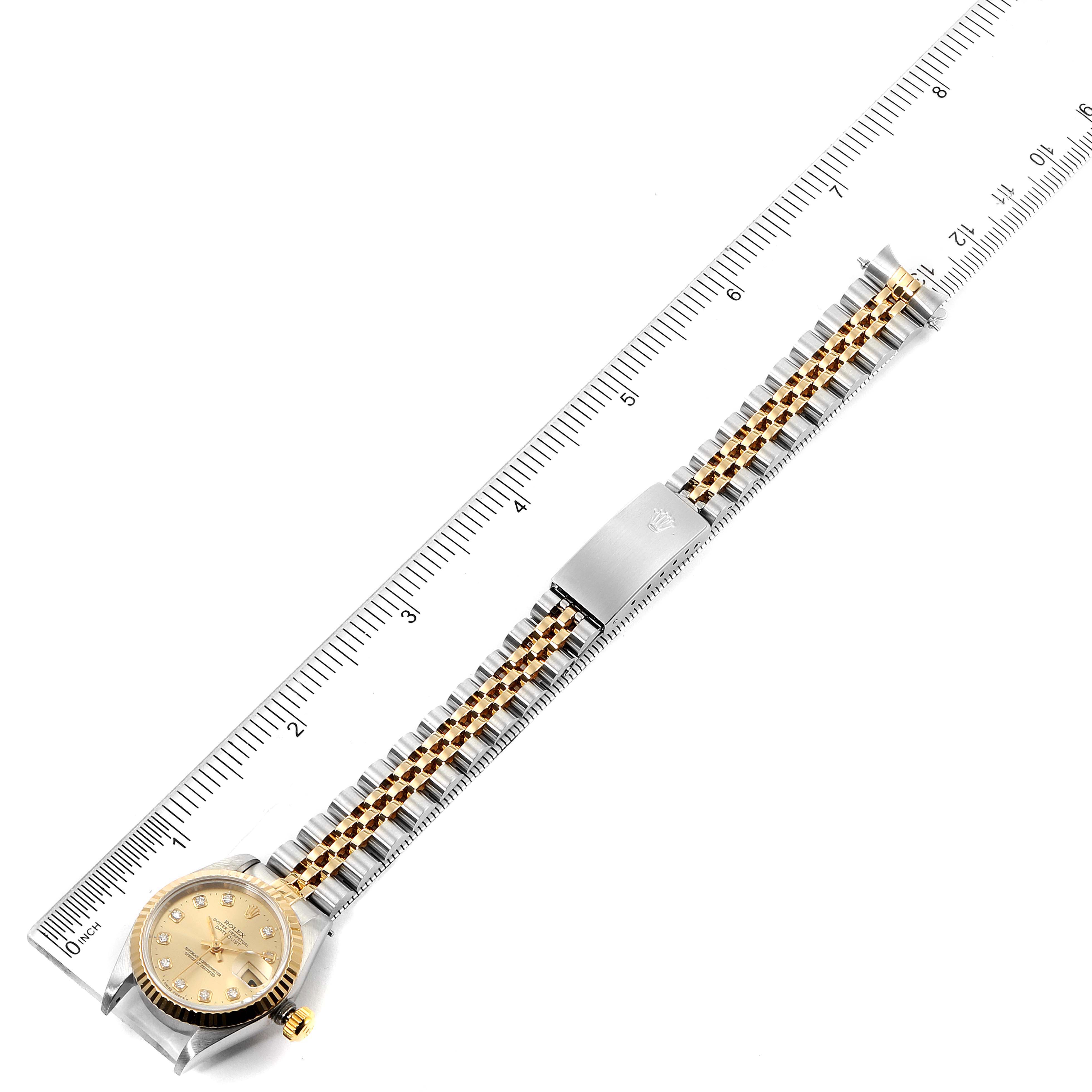 The Rolex Datejust 69173 Women
s Steel and Gold (two tone) Champagne Dial 69173 Women
s Steel and Gold (two tone) Champagne Dial watch is shown from above, highlighting the dial, bracelet, clasp, and positioned against a ruler for scale.