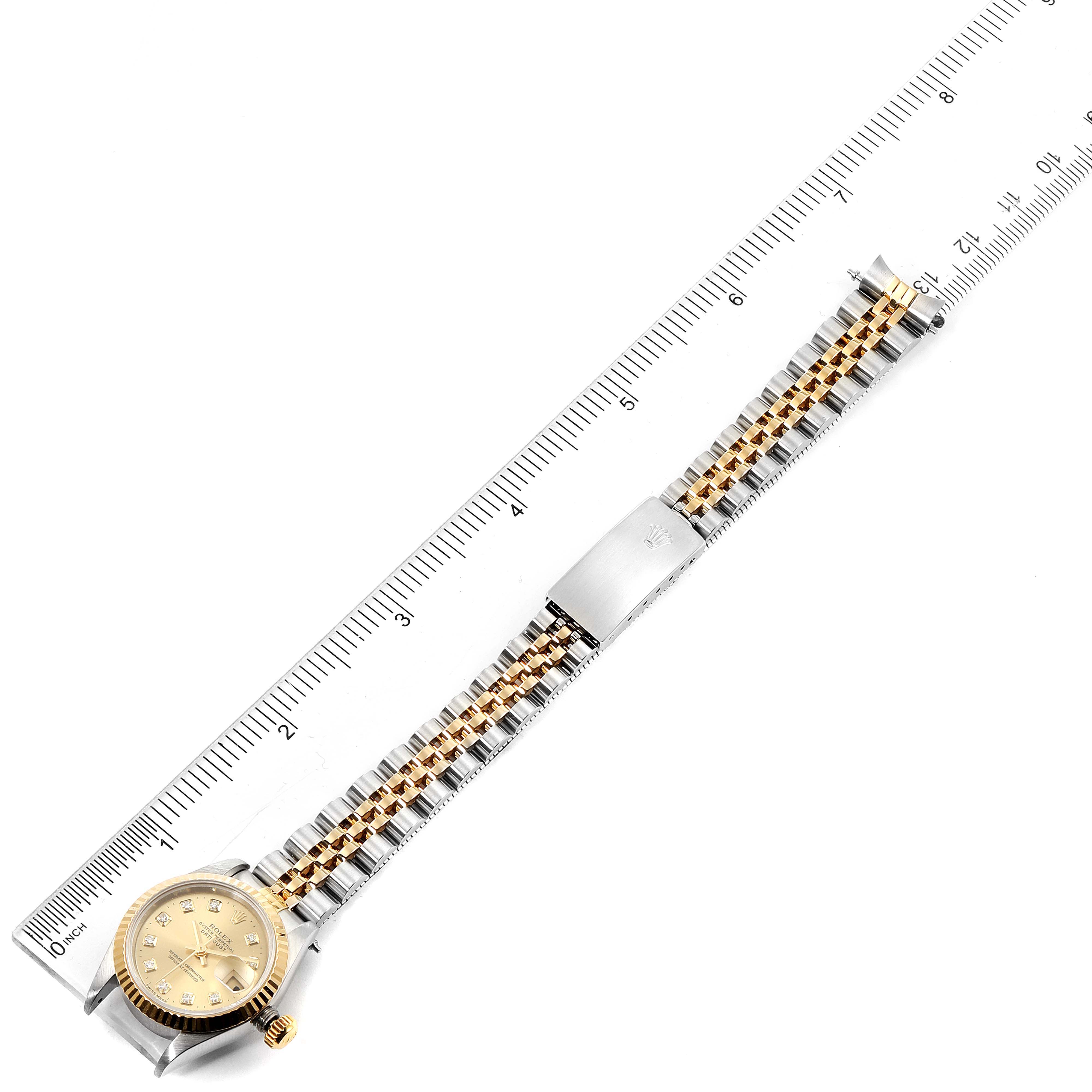 This image shows a top-down view of a Rolex Datejust 69173 Women
s Steel and Gold (two tone) Champagne Dial 69173 Women
s Steel and Gold (two tone) Champagne Dial watch, including the entire band, clasp, and face, placed next to a ruler.