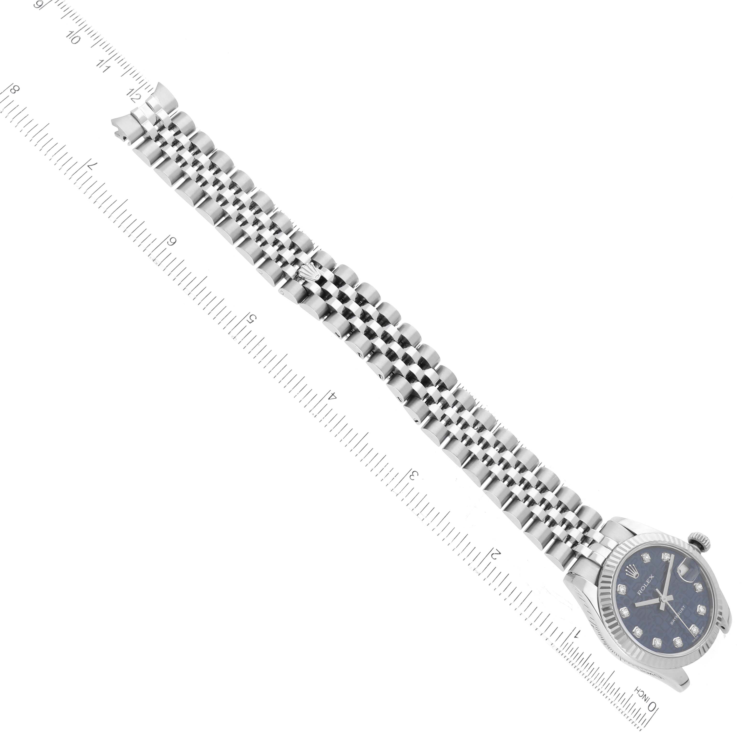 The image shows a top view of a Rolex Mid-Size 178274 Women
s Stainless Steel Blue Dial 178274 Women
s Stainless Steel Blue Dial model, displaying the watch face, bracelet, and part of a ruler for scale.