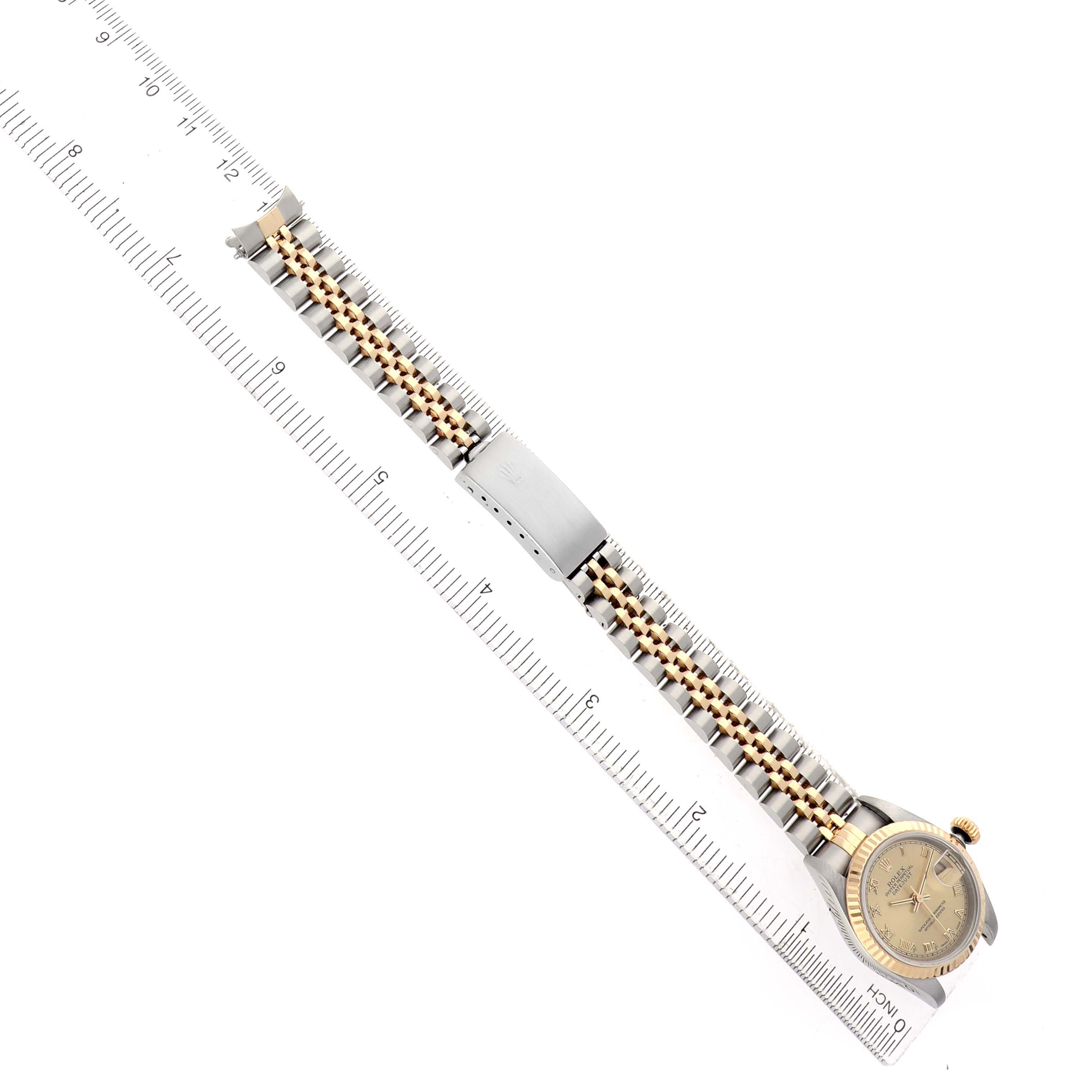 The Rolex Datejust 69173 Women's Steel and Gold (two tone) Champagne Dial watch is shown from an overhead angle, displaying the full bracelet, clasp, and face next to a ruler.