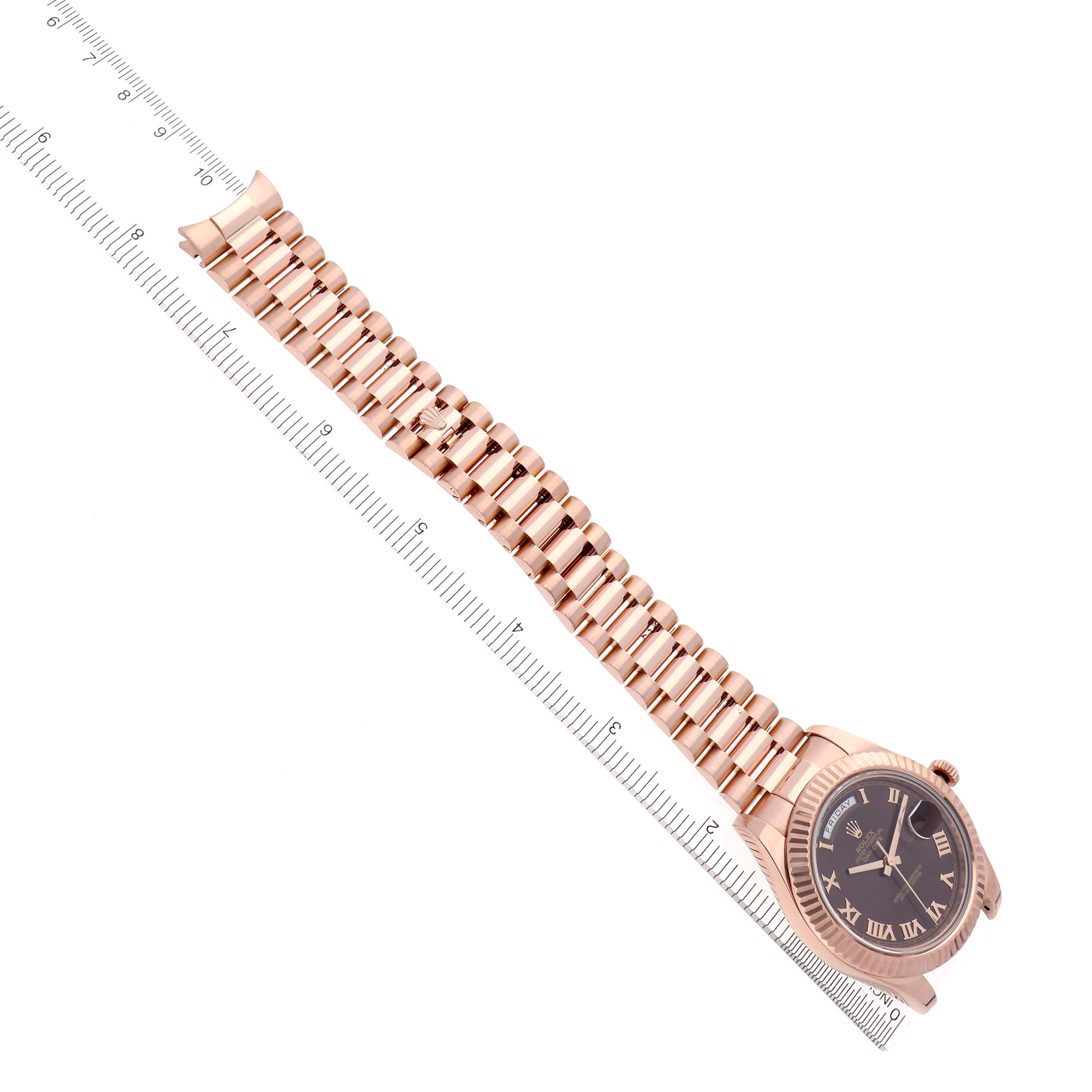 The Rolex President 218235 Men's Rose Gold Brown Dial 218235 Men's Rose Gold Brown Dial model watch is shown from an overhead angle, displaying the case, dial, and full bracelet alongside a ruler.