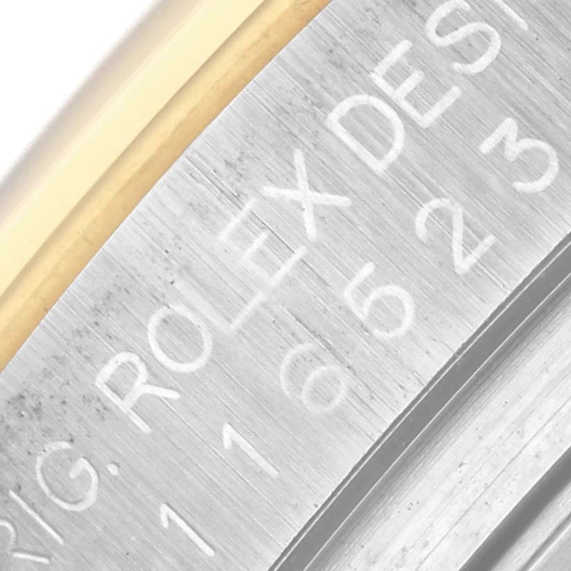 The image shows an angled close-up of the engraved edge of a Rolex Daytona 116523 Men's Steel and Gold (two tone) White Dial 116523 Men's Steel and Gold (two tone) White Dial watch, displaying the model details.