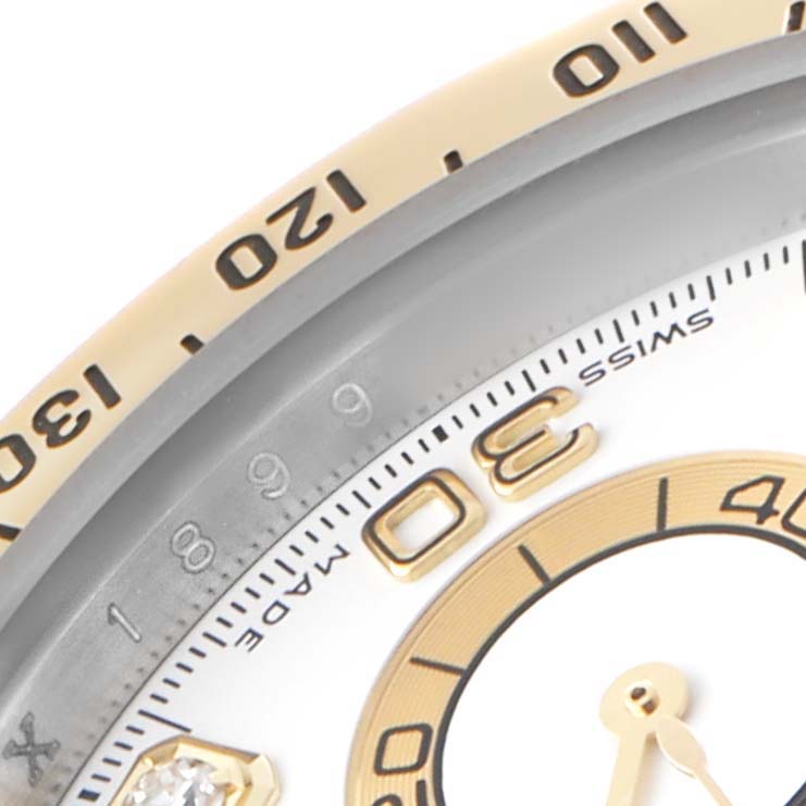 The image shows a close-up of the Rolex Daytona 116523 Men's Steel and Gold (two tone) White Dial watch bezel, partial dial, and indices at a diagonal angle.
