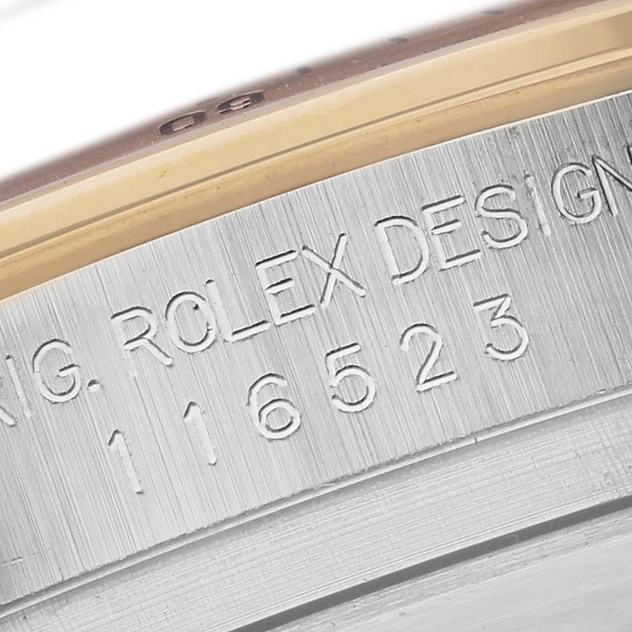 The image shows a close-up of the edge of a Rolex Daytona 116523NR Men's Steel and Gold (two tone) Mother of Pearl Dial 116523NR Men's Steel and Gold (two tone) Mother of Pearl Dial case with engraved design and model number.