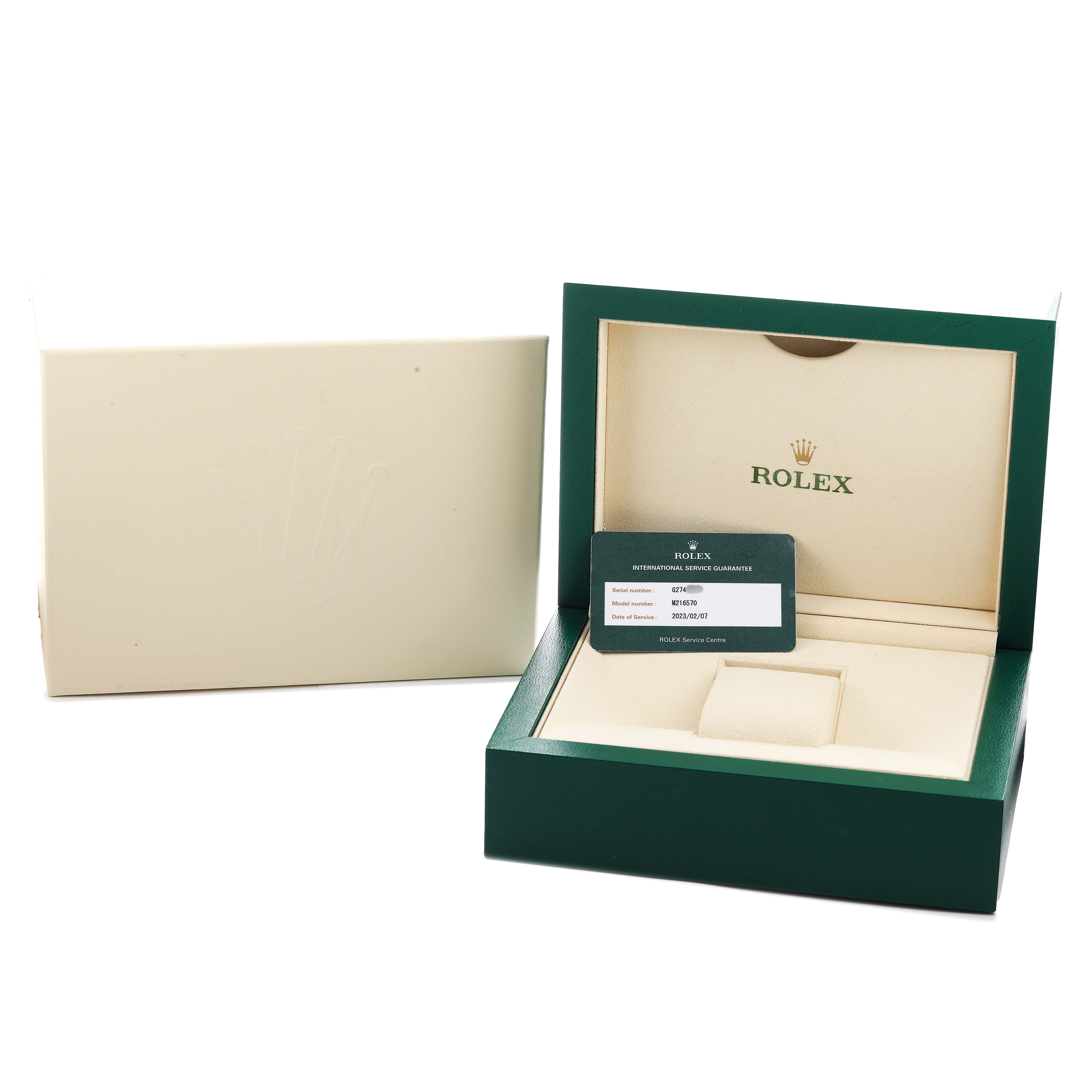 The Rolex Explorer 216570 Men's Stainless Steel White Dial packaging includes an open green box showing the inner cushion and a warranty card, with the outer box displayed beside it.