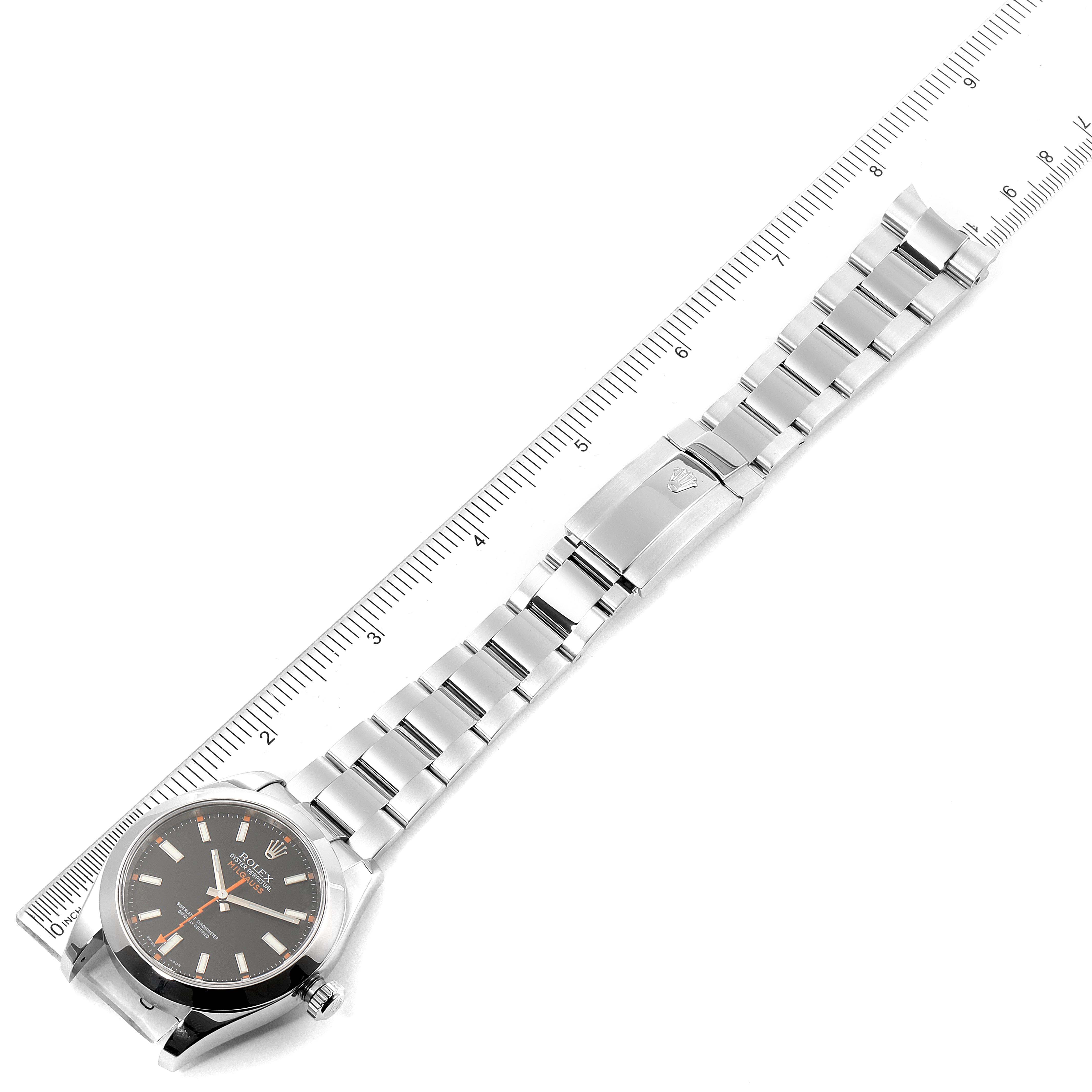 The image shows the entire length of the Rolex Milgauss 116400 Men
s Stainless Steel Black Dial 116400 Men
s Stainless Steel Black Dial, including its face, bracelet, and clasp, laid next to a ruler.
