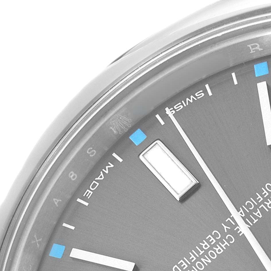 The image shows a close-up of the dial and bezel of the Rolex Oyster Perpetual 114300 Men's Stainless Steel Silver Dial, focusing on the hour markers and text.