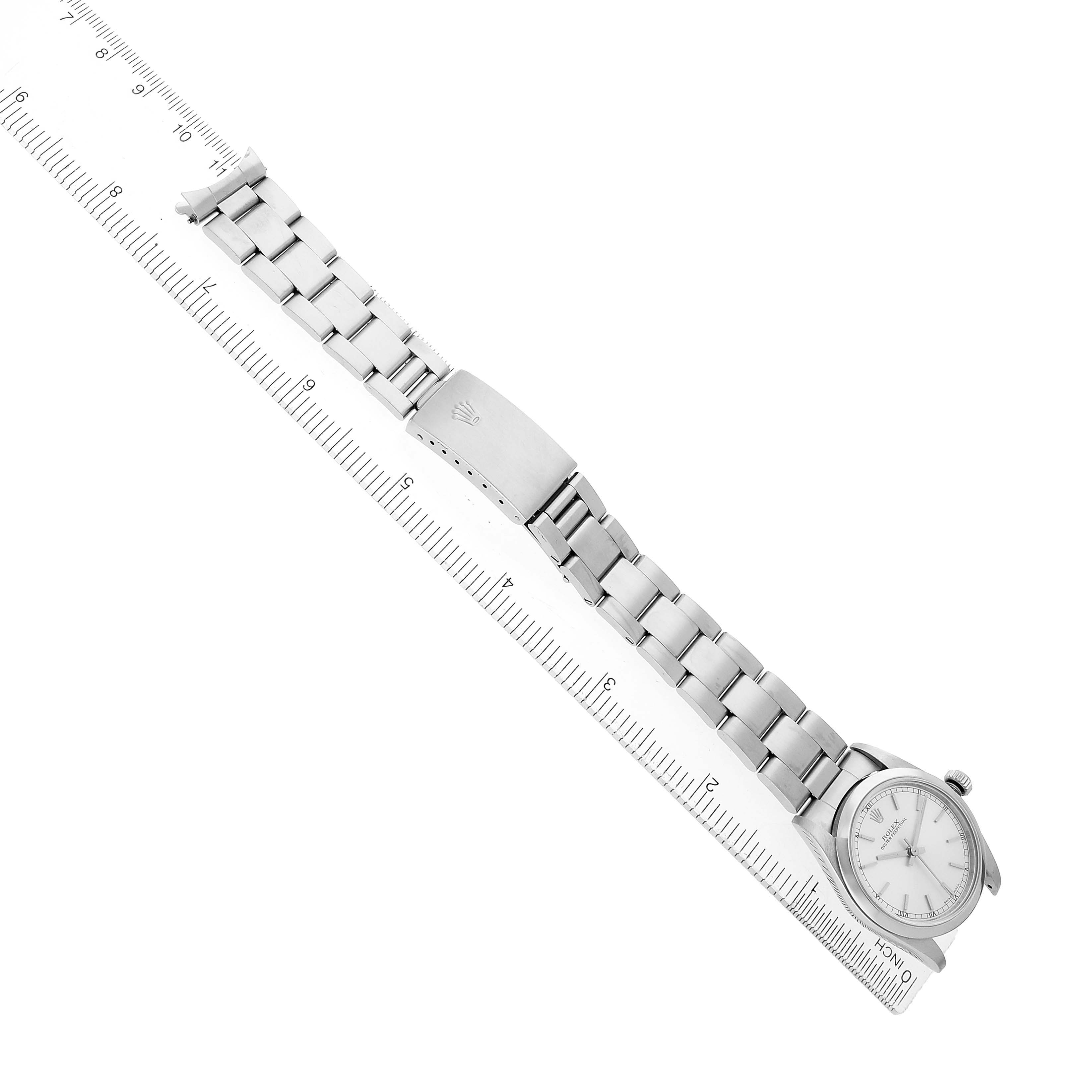The image shows a side view of a Rolex Oyster Perpetual 77080 Women's Stainless Steel Silver Dial watch with its metal bracelet and clasp next to a ruler.