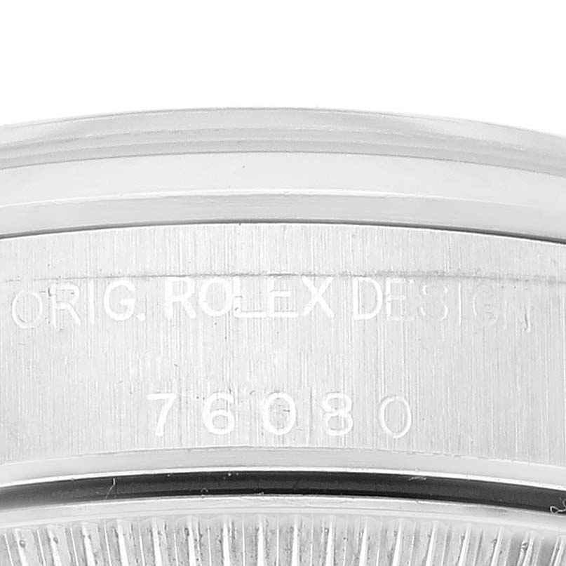 This image shows a close-up of the engraved bezel on a Rolex Oyster Perpetual 76080 Women's Stainless Steel Orange Dial 76080 Women's Stainless Steel Orange Dial watch, highlighting the model and brand markings.